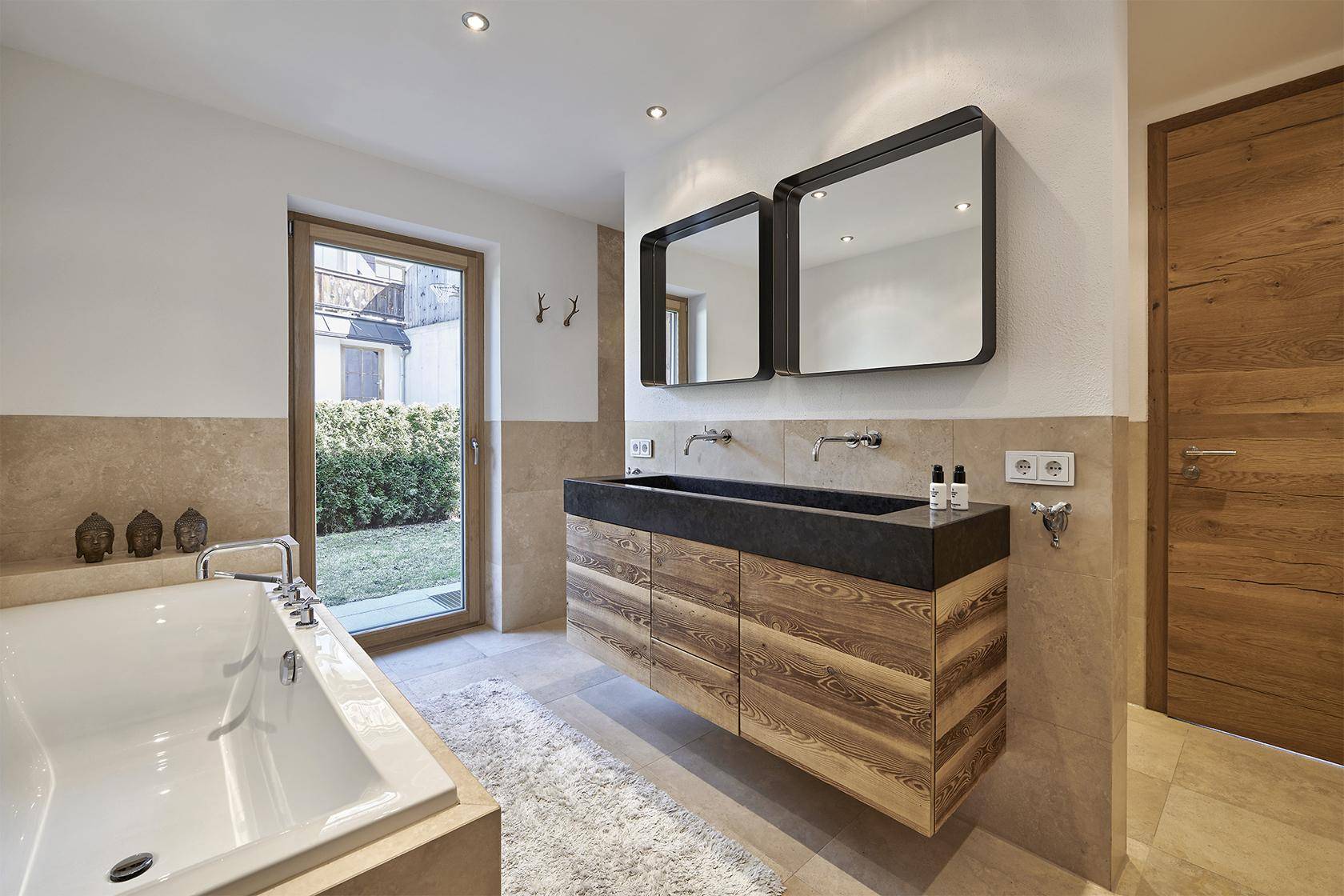 Modernes Badezimmer mit Badewanne, Doppelwaschbecken und Fenster für Tageslicht.