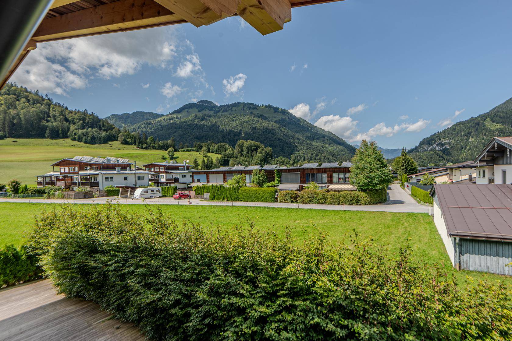 Weitläufiger Blick über grüne Wiesen und die umliegende Berglandschaft von der Unterkunft aus.