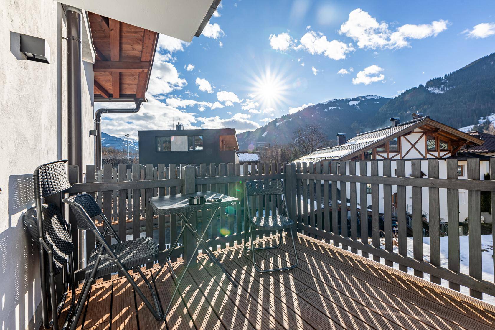 Sonniger Balkon mit Holzboden und Sitzgelegenheiten, bietet einen weiten Blick auf die Berge.