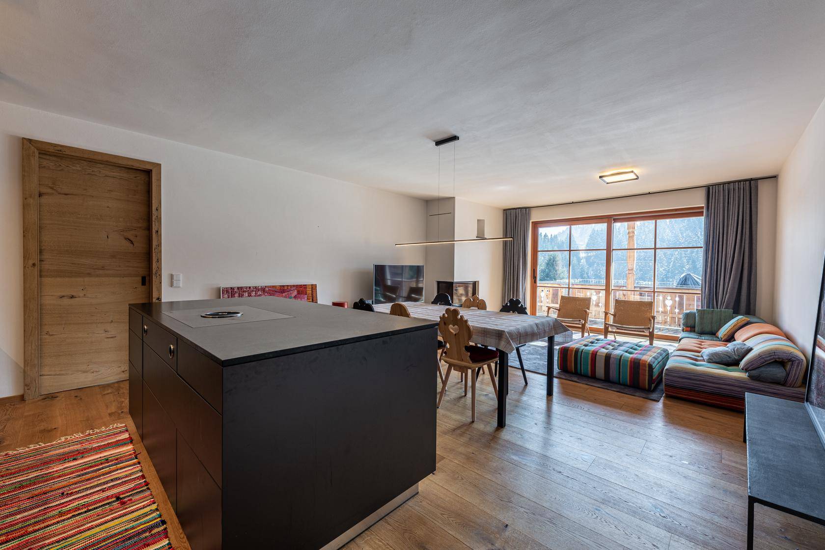 Heller Wohn-Essbereich mit moderner Küche, Holzboden und Zugang zum Balkon.
