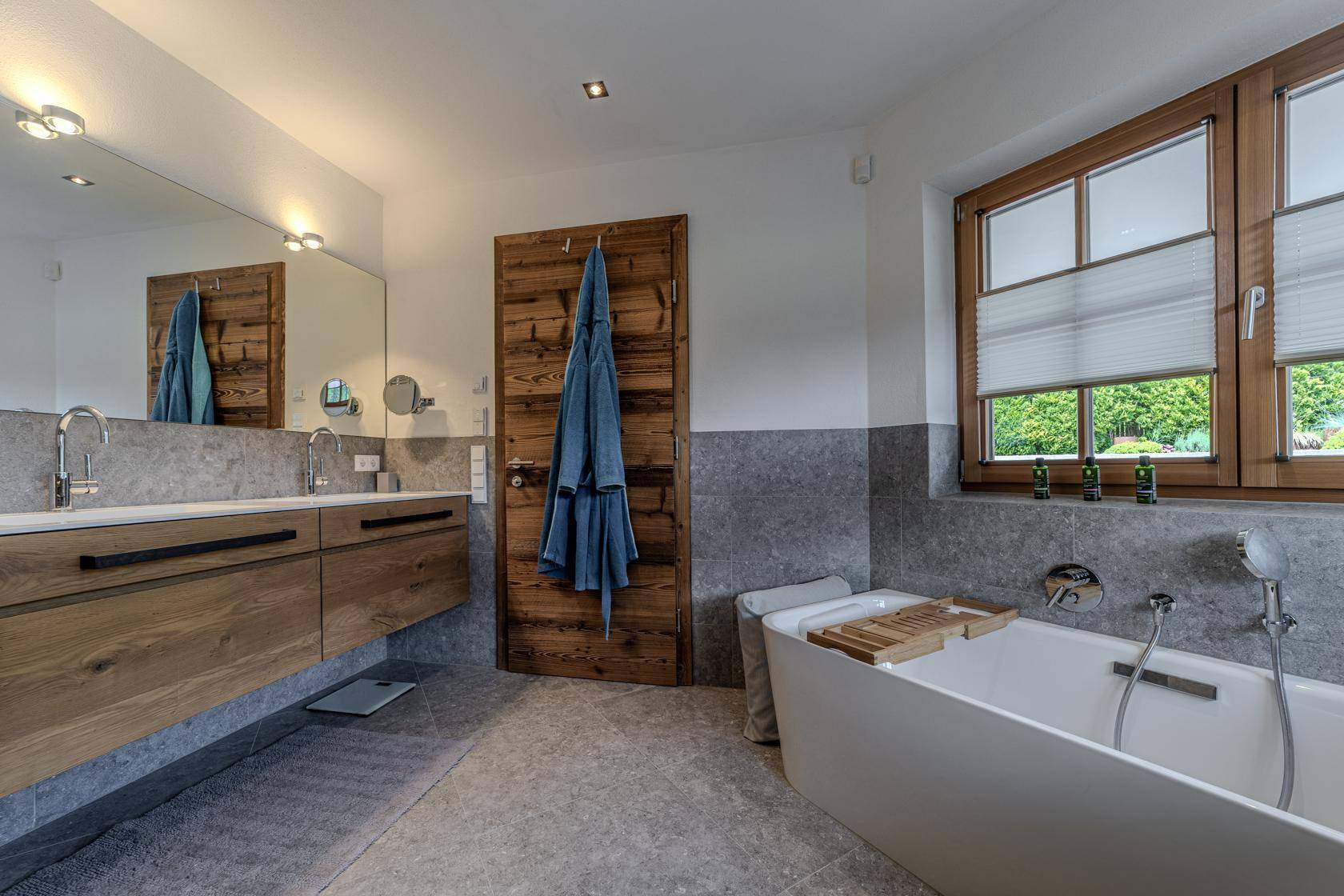 Modernes Badezimmer mit freistehender Badewanne, Doppelwaschbecken und Fenster.