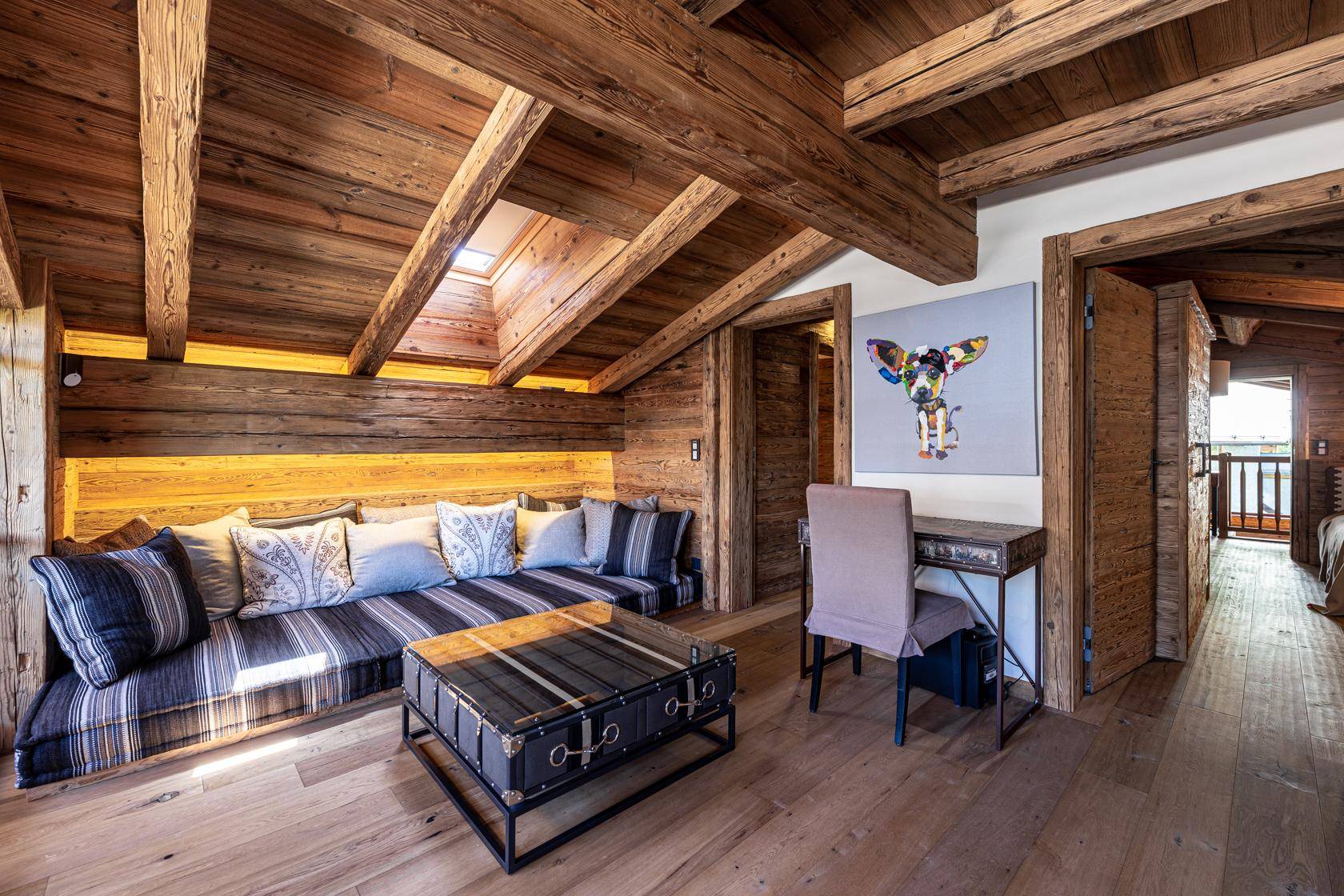 Gemütlicher Wohnbereich im Dachgeschoss mit Holzvertäfelung, integriertem Sofa und Dachfenster.