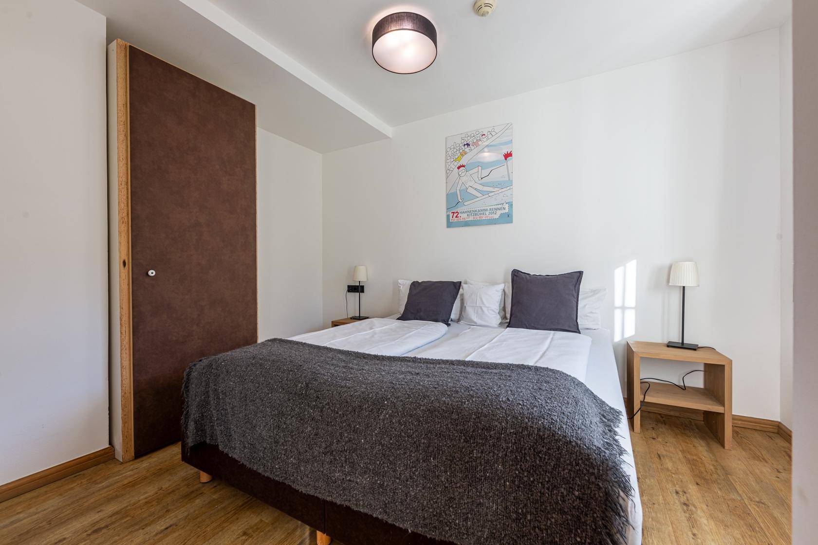 Helles Schlafzimmer mit Doppelbett, Nachttischen und einem modernen Kunstwerk an der Wand.