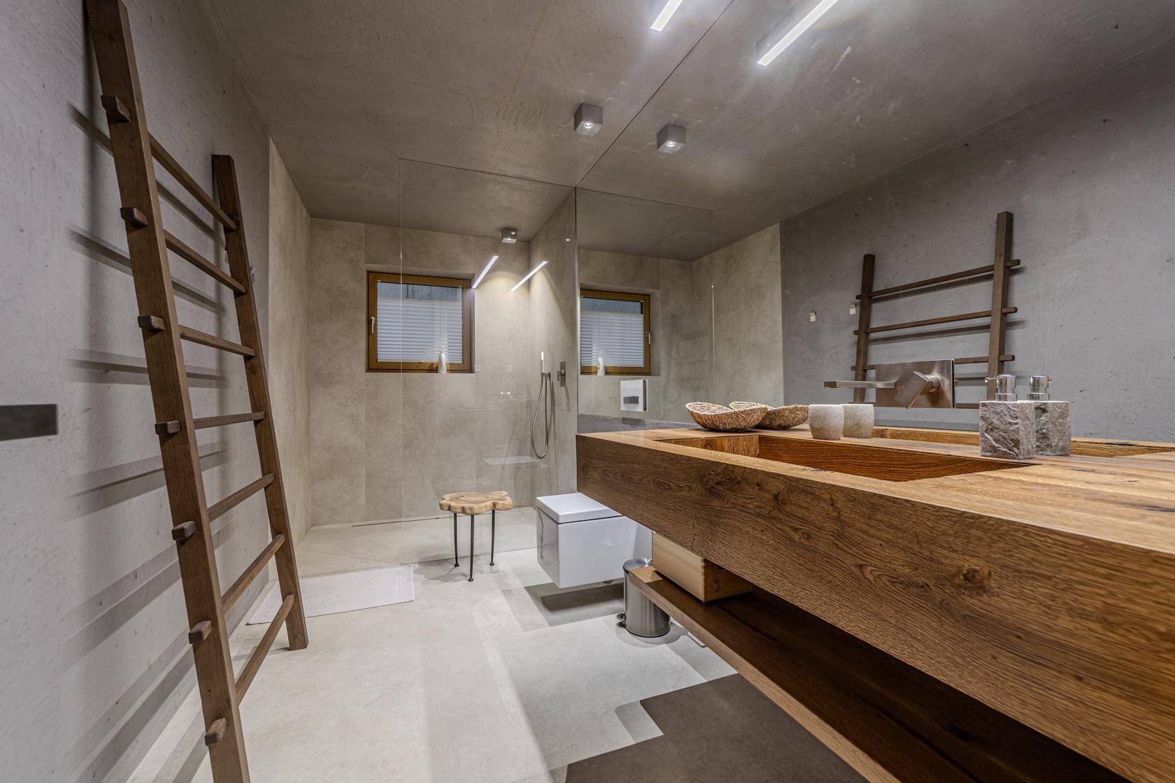Modernes Badezimmer mit begehbarer Dusche, Holzwaschtisch und zwei Fenstern.