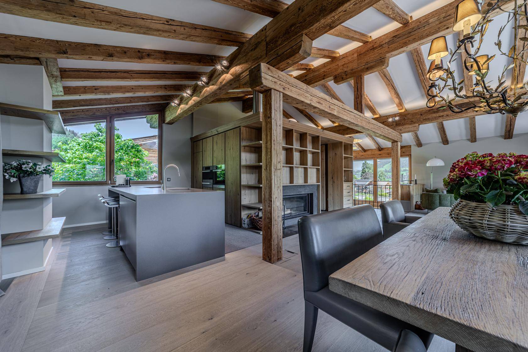 Moderne Küche mit Kochinsel, integriertem Kamin und Holzbalken.