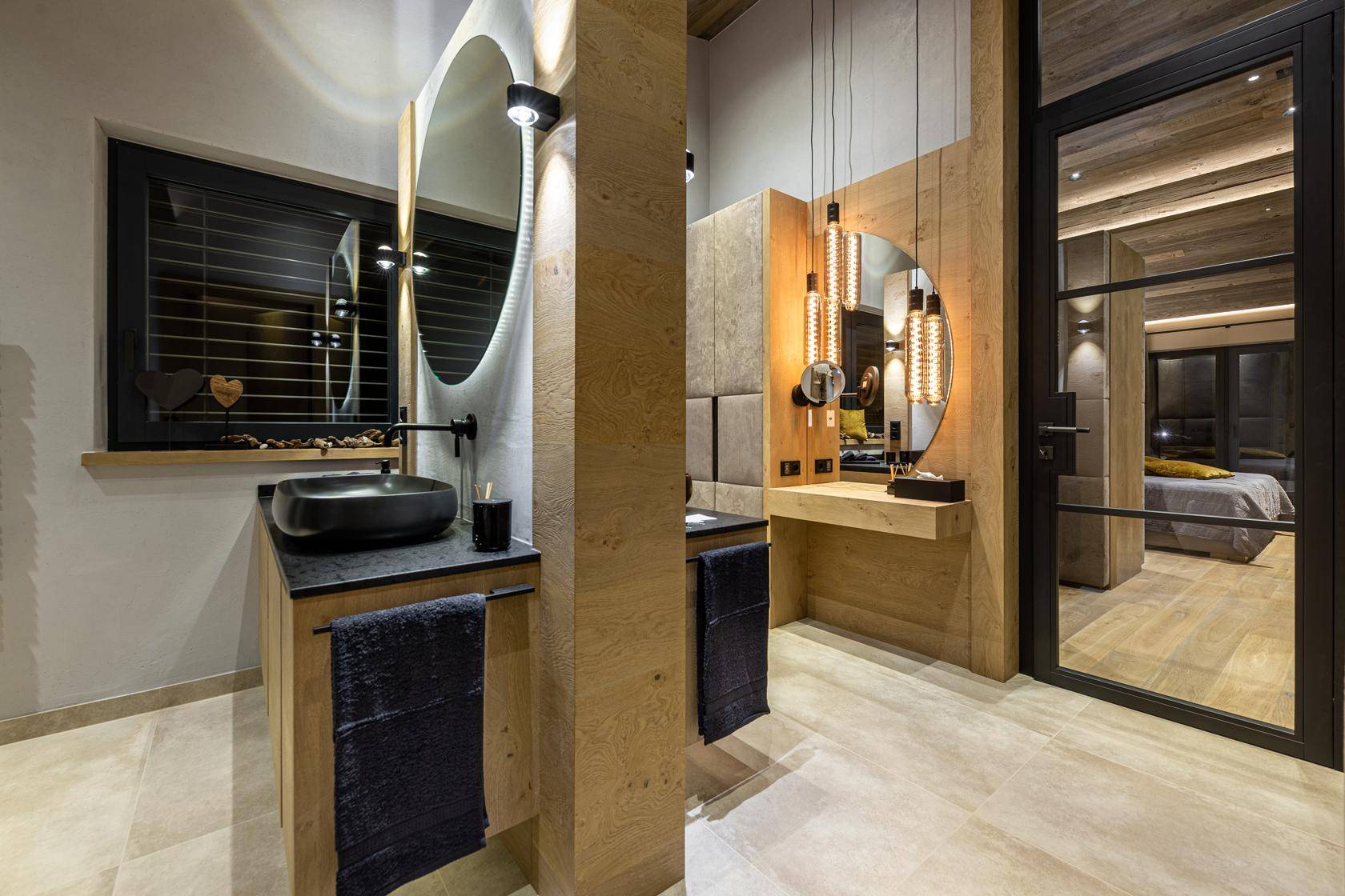 Elegantes Badezimmer mit zwei Waschtischen, runden Spiegeln und Holzelementen.