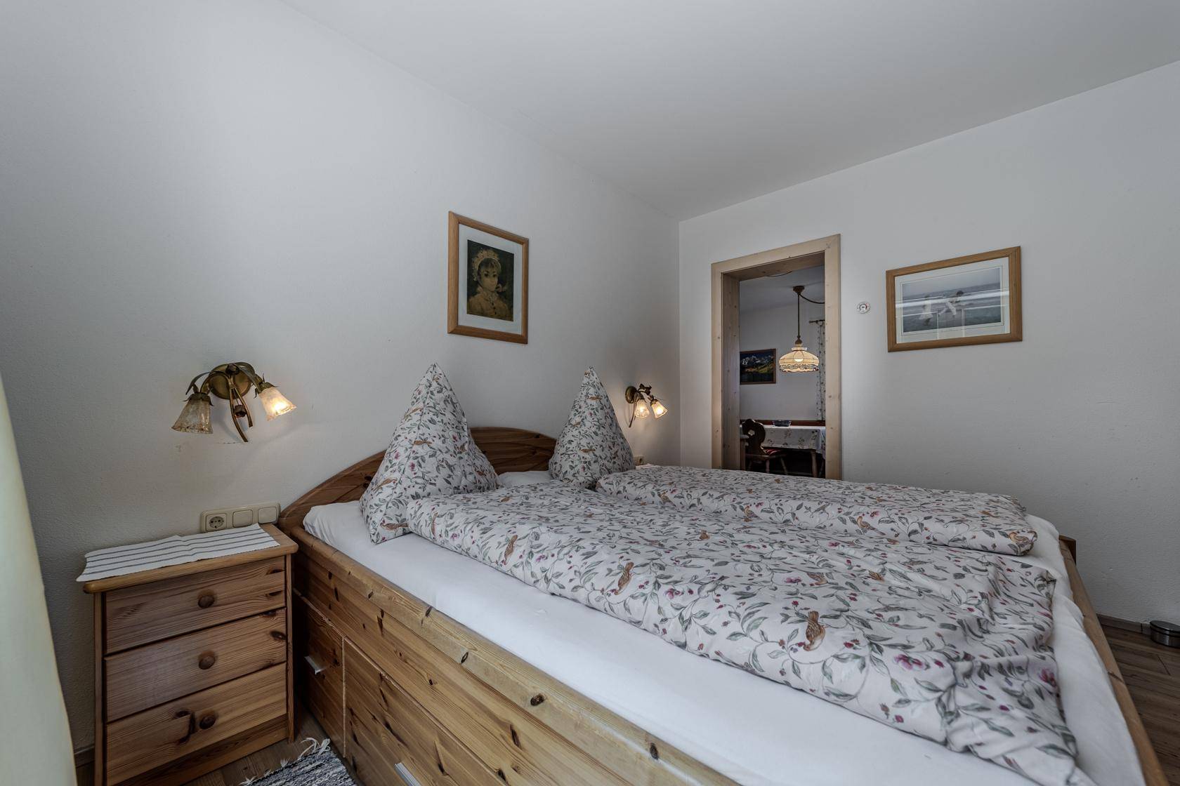 Schlafzimmer mit traditionellem Holzdoppelbett und Blick in den angrenzenden Raum.
