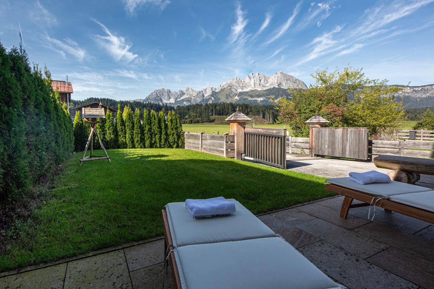 Gepflegter Garten mit Liegestühlen, Rasenfläche und beeindruckendem Bergblick.