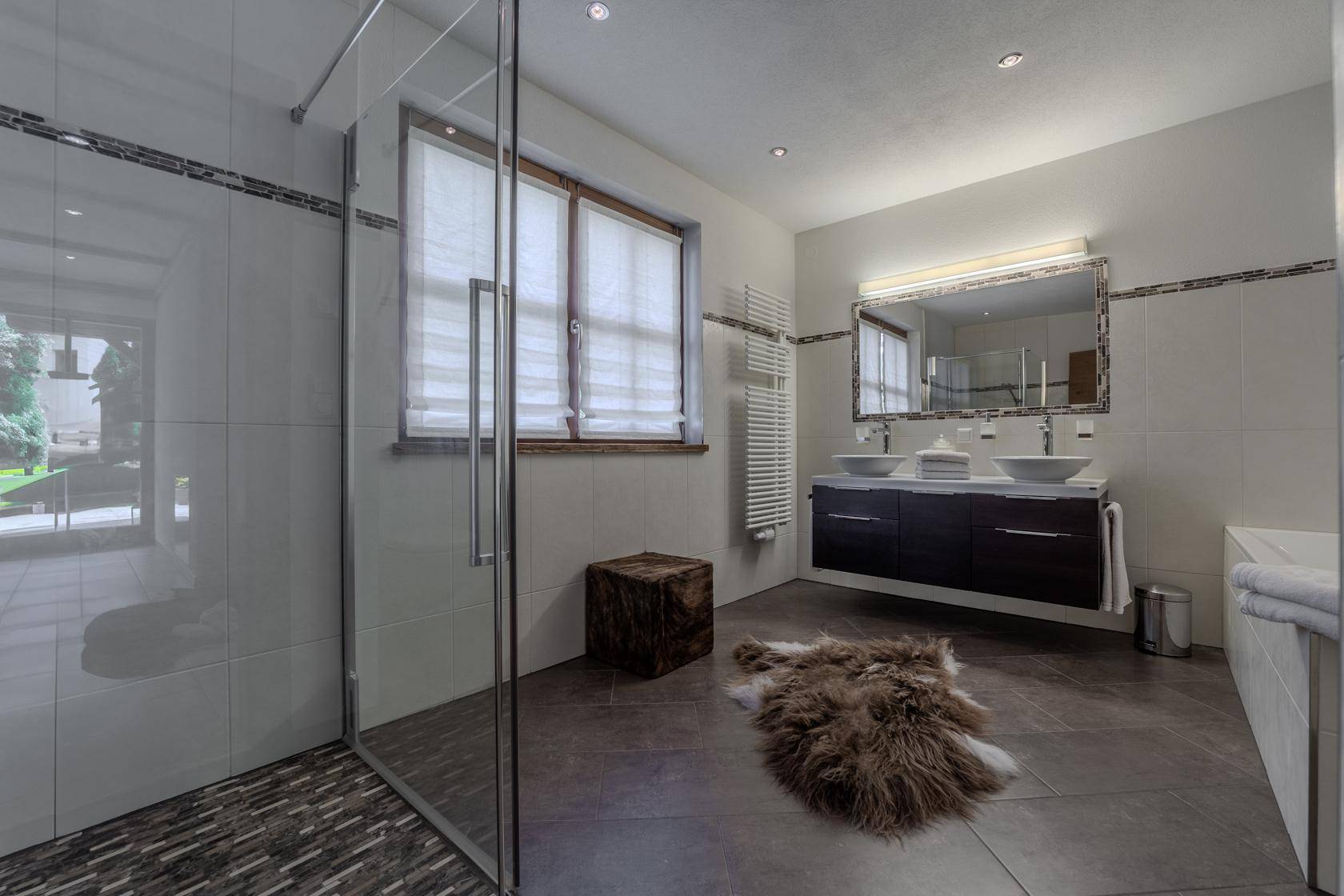 Modernes Badezimmer mit Doppelwaschbecken, großer Dusche und beheiztem Handtuchhalter.