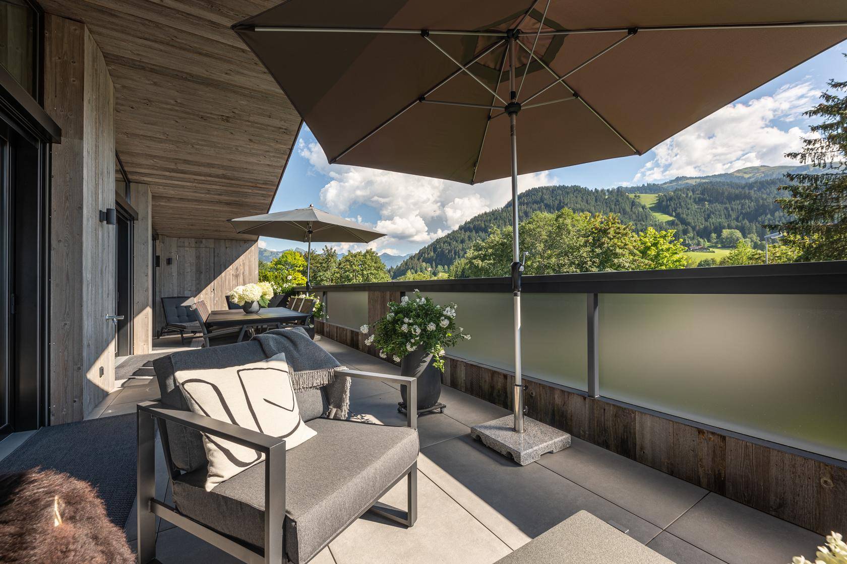 Große, möblierte Terrasse mit Sonnenschirmen und herrlichem Blick auf die umliegende Berglandschaft.