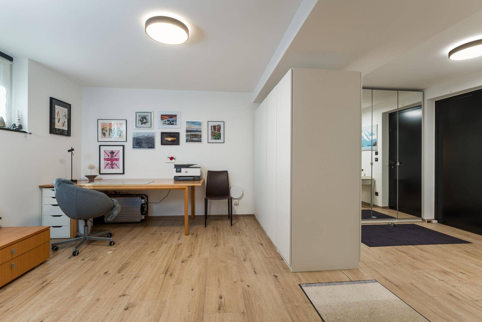 Helles Arbeitszimmer mit Holzboden, Schreibtisch und viel Stauraum.