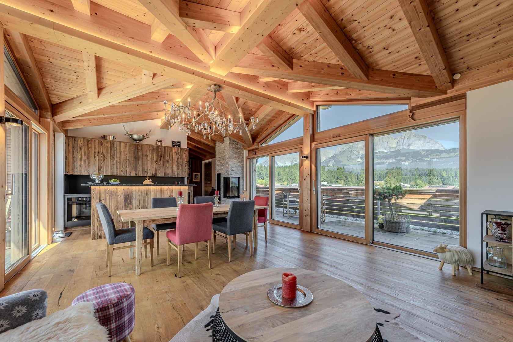 Gemütlicher Wohn-Essbereich mit Holzelementen, Kamin und Panoramablick auf die Berge.