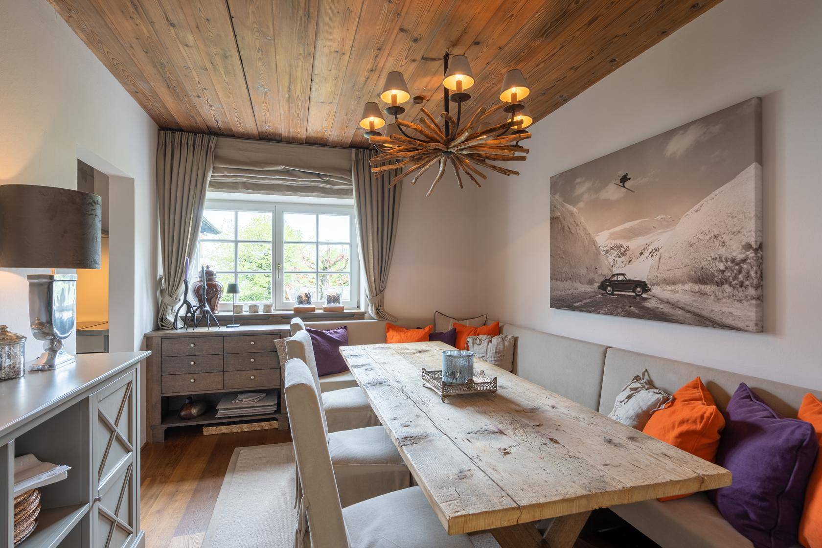 Rustikaler Essbereich mit Holztisch, gepolsterter Sitzbank und Holzdecke.