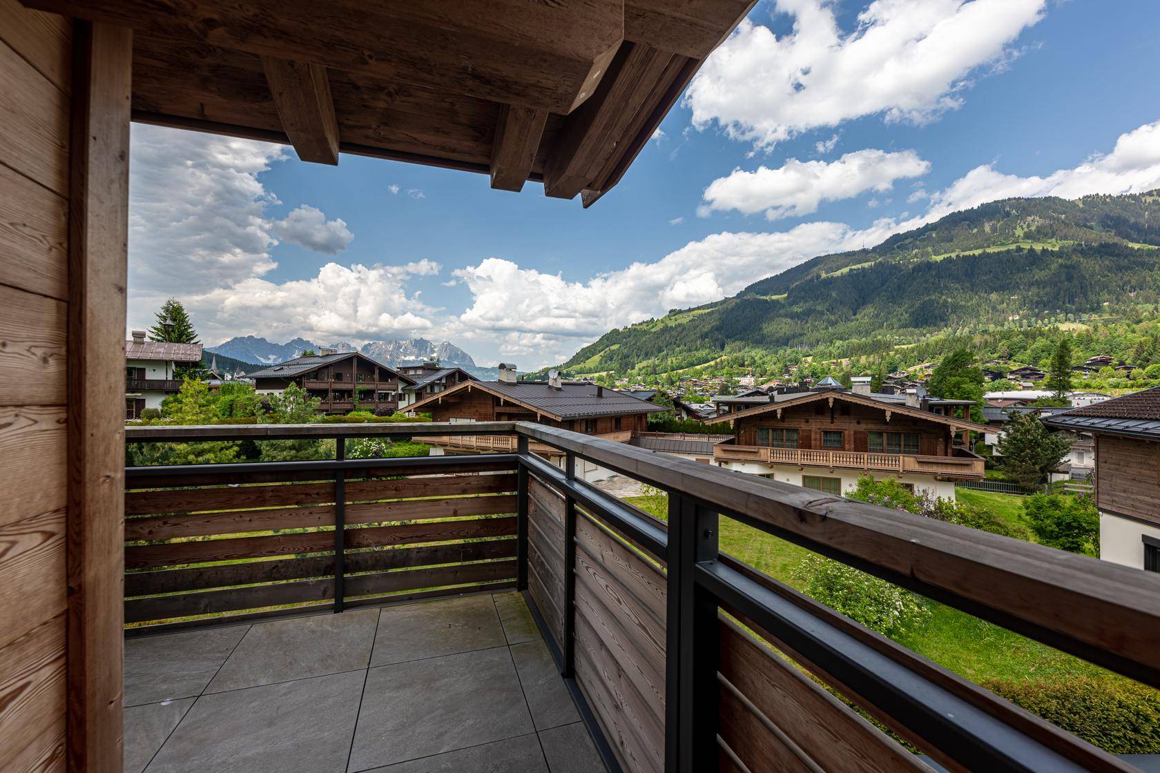 Kleiner Balkon mit Holzelementen und weitem Blick auf die umliegende Berglandschaft.