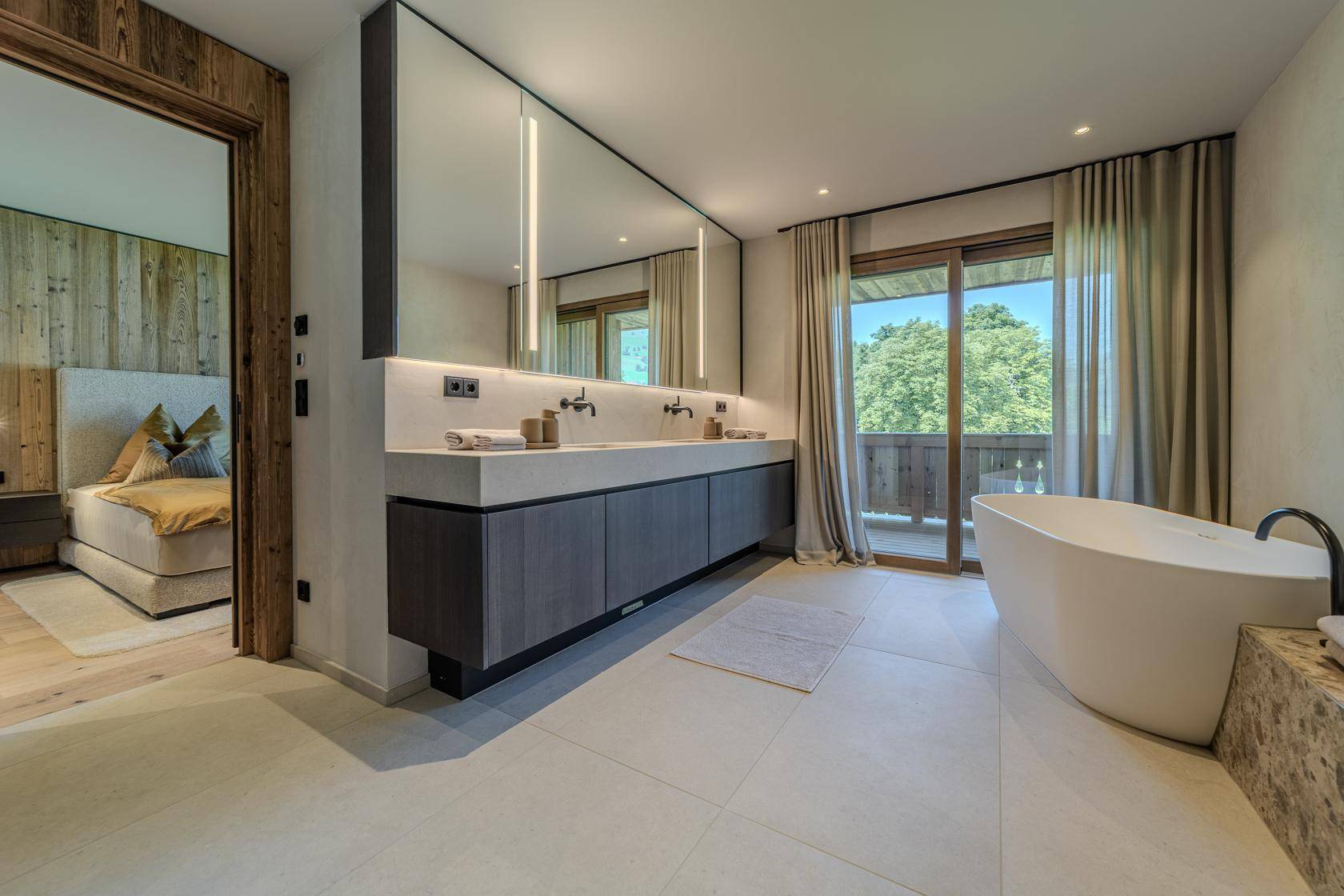 Elegantes Badezimmer mit Doppelwaschbecken, großem Spiegel und Zugang zum Schlafzimmer.