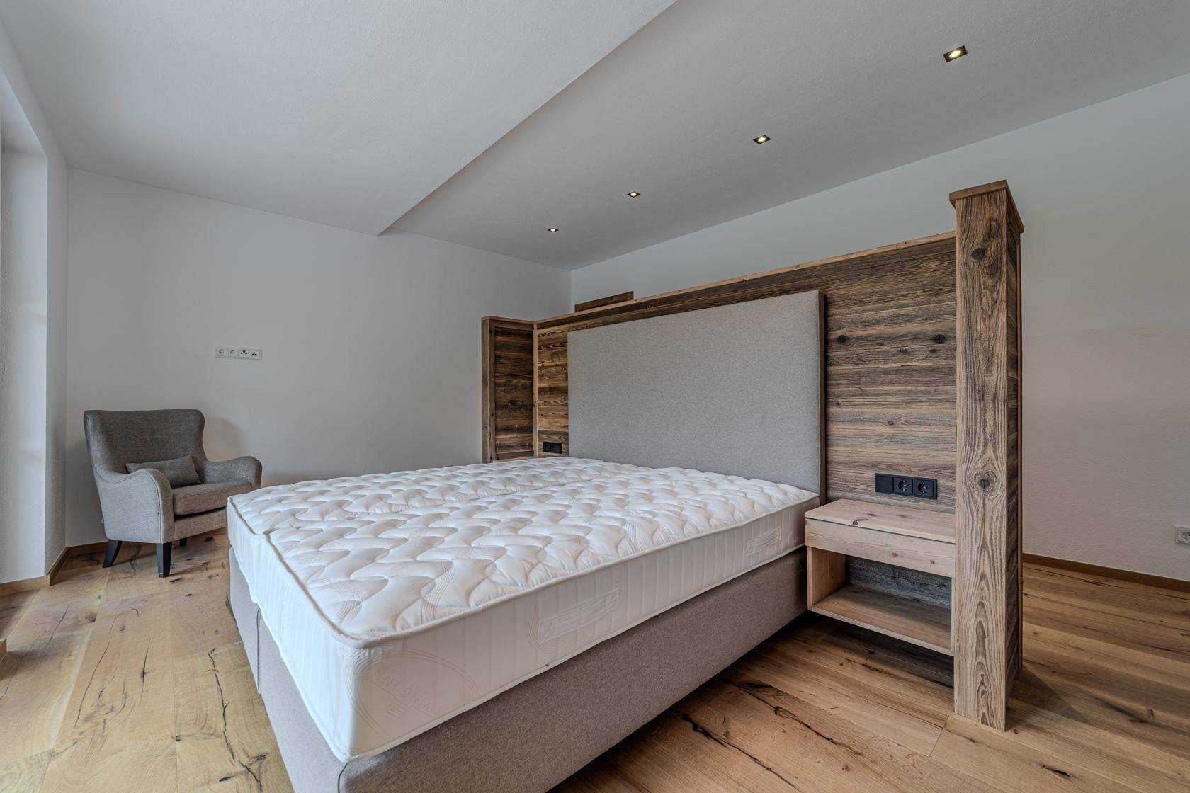 Gemütliches Schlafzimmer mit Holzboden und maßgefertigtem Holzbettrahmen mit integrierten Nachttischen.
