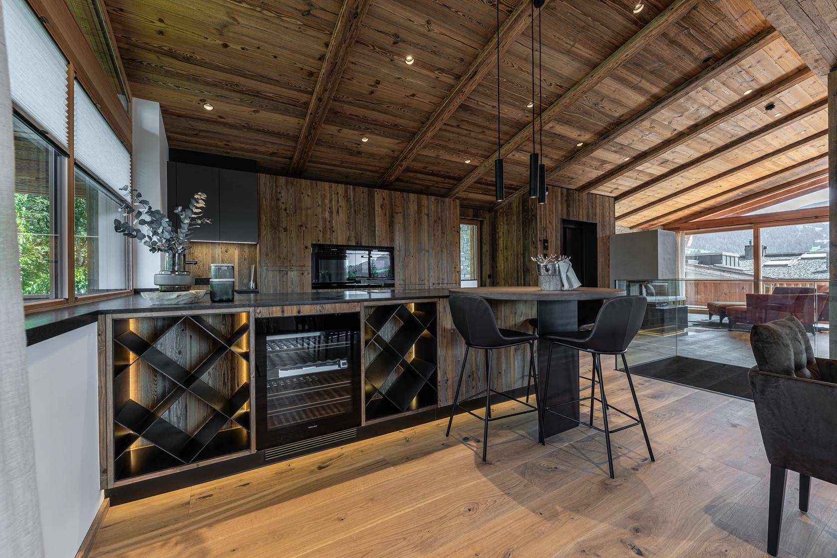 Moderne Küche im Chalet-Stil mit Holzwänden, Weinkühler und Bartresen, offen zum Wohnbereich.