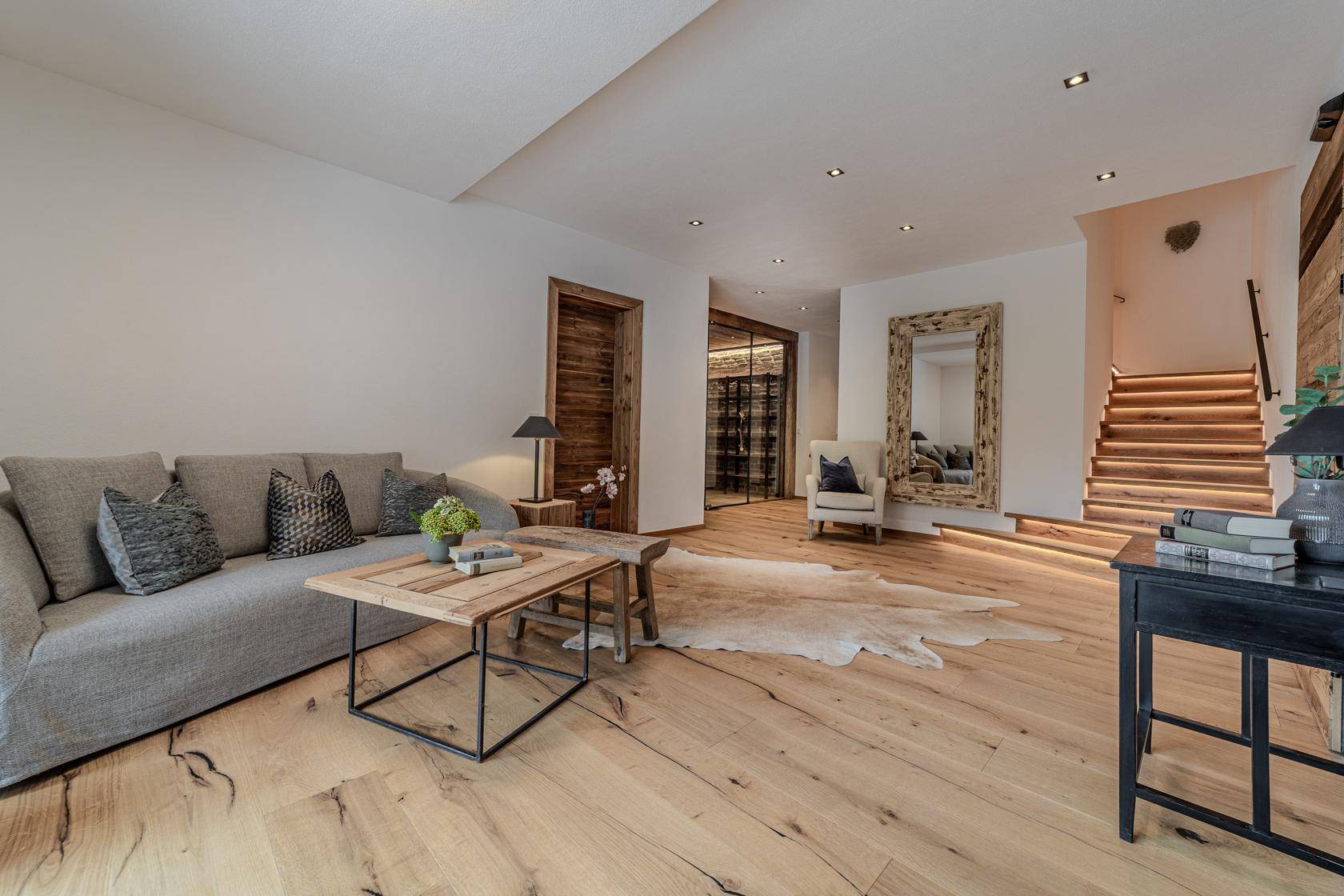 Stilvoller Wohnbereich mit Holzboden, bequemer Couch und beleuchteter Holztreppe.