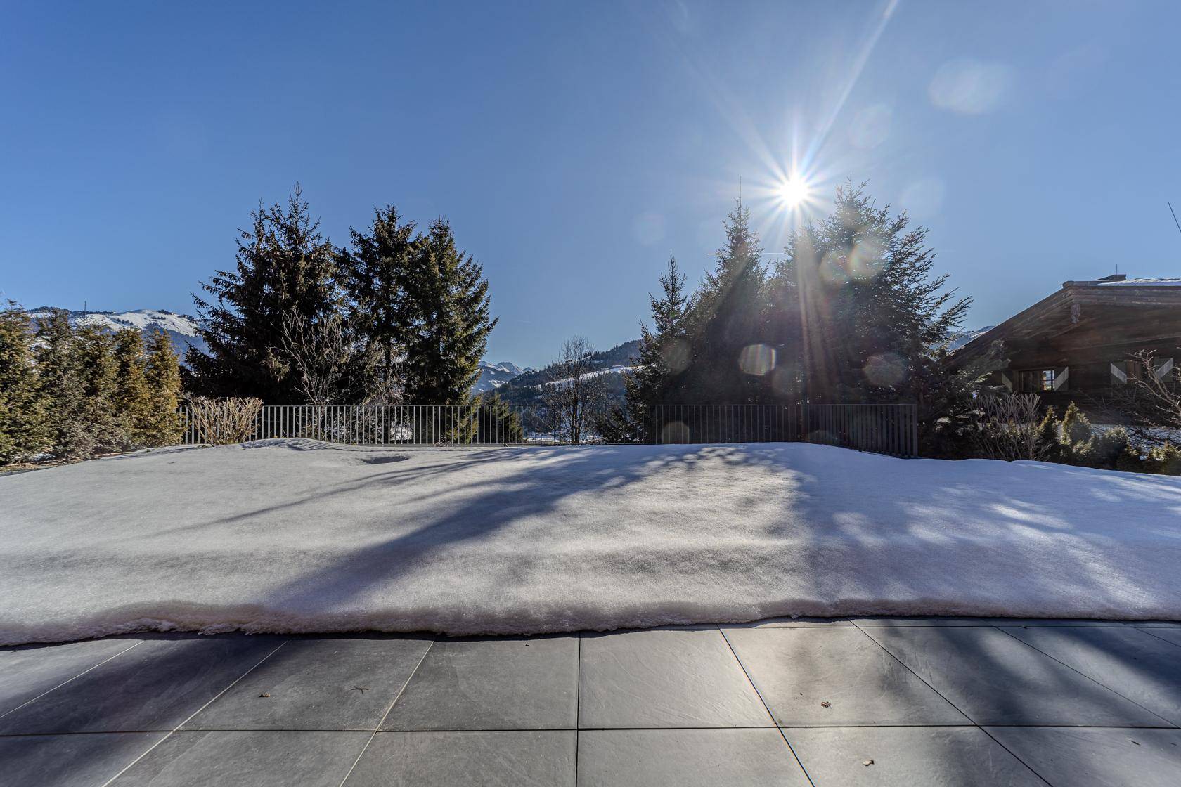 Sonniger Terrassenbereich mit Schnee und weitem Blick auf die umliegende Berglandschaft.
