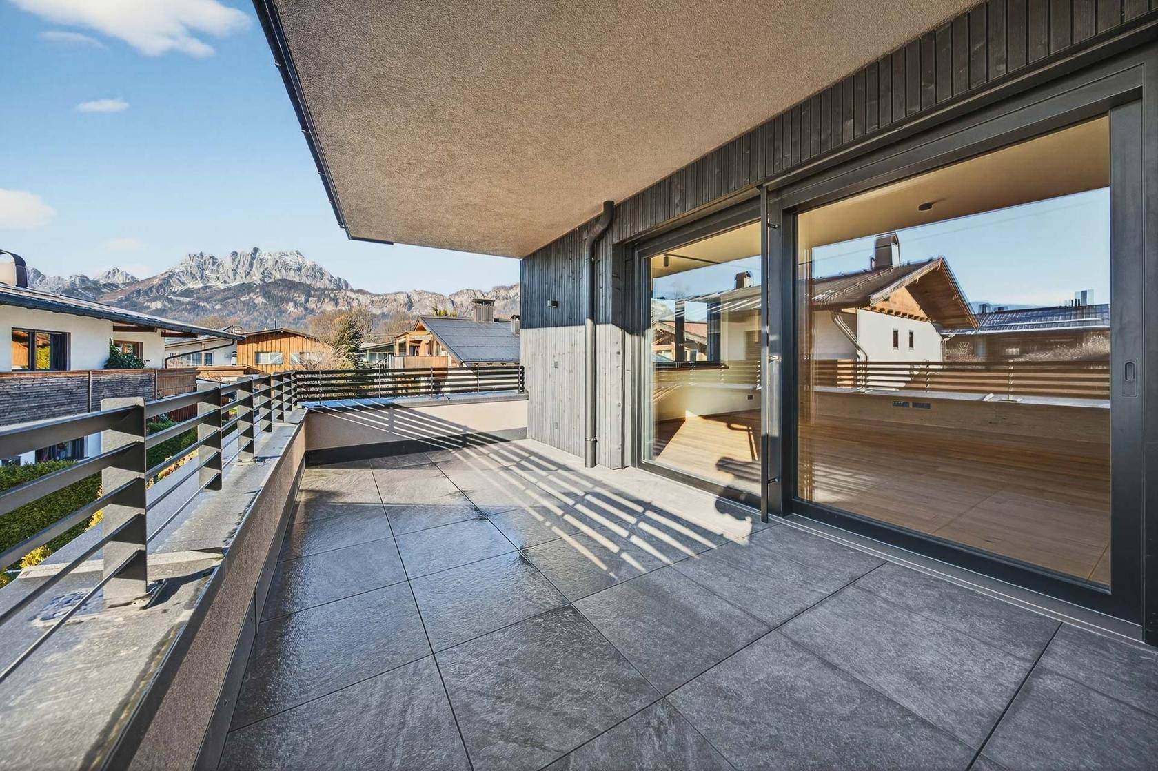 Großer Balkon mit Fliesenboden, Metallgeländer und beeindruckendem Bergblick.
