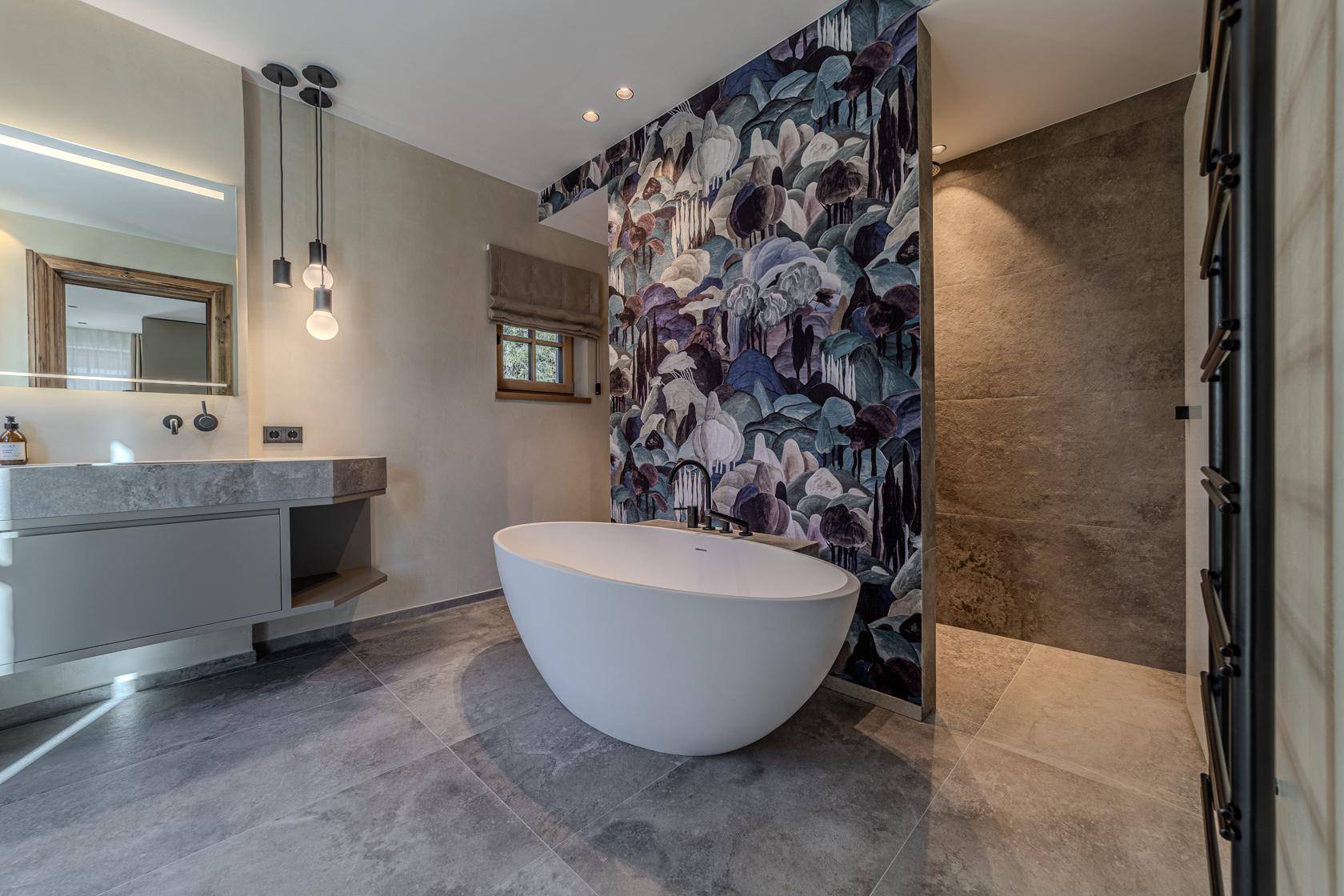 Modernes Badezimmer mit freistehender Badewanne, großformatigen Fliesen und floraler Akzentwand.