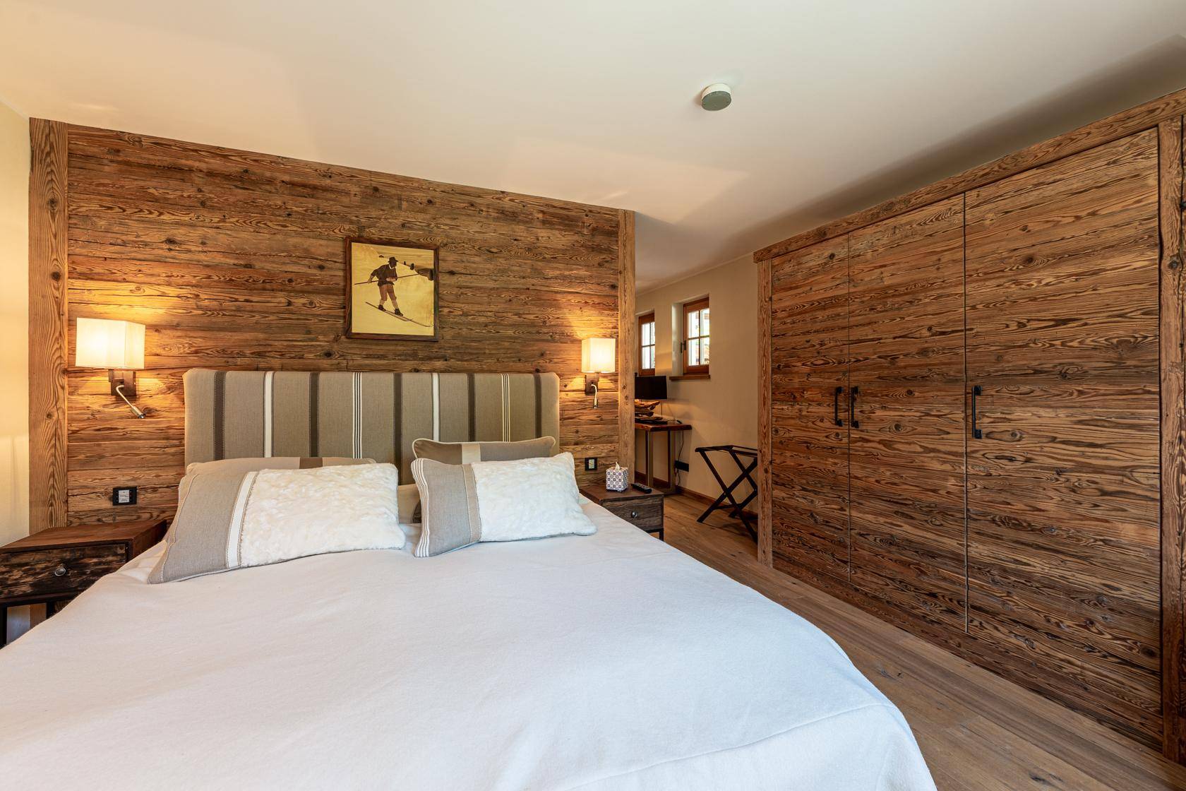 Gemütliches Schlafzimmer mit Holzwandvertäfelung, großem Bett und integriertem Holzschrank.