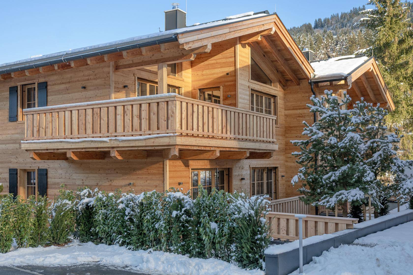 Charmantes Holzchalet mit Balkon und verschneiter Umgebung, eingebettet in eine malerische Berglandschaft.