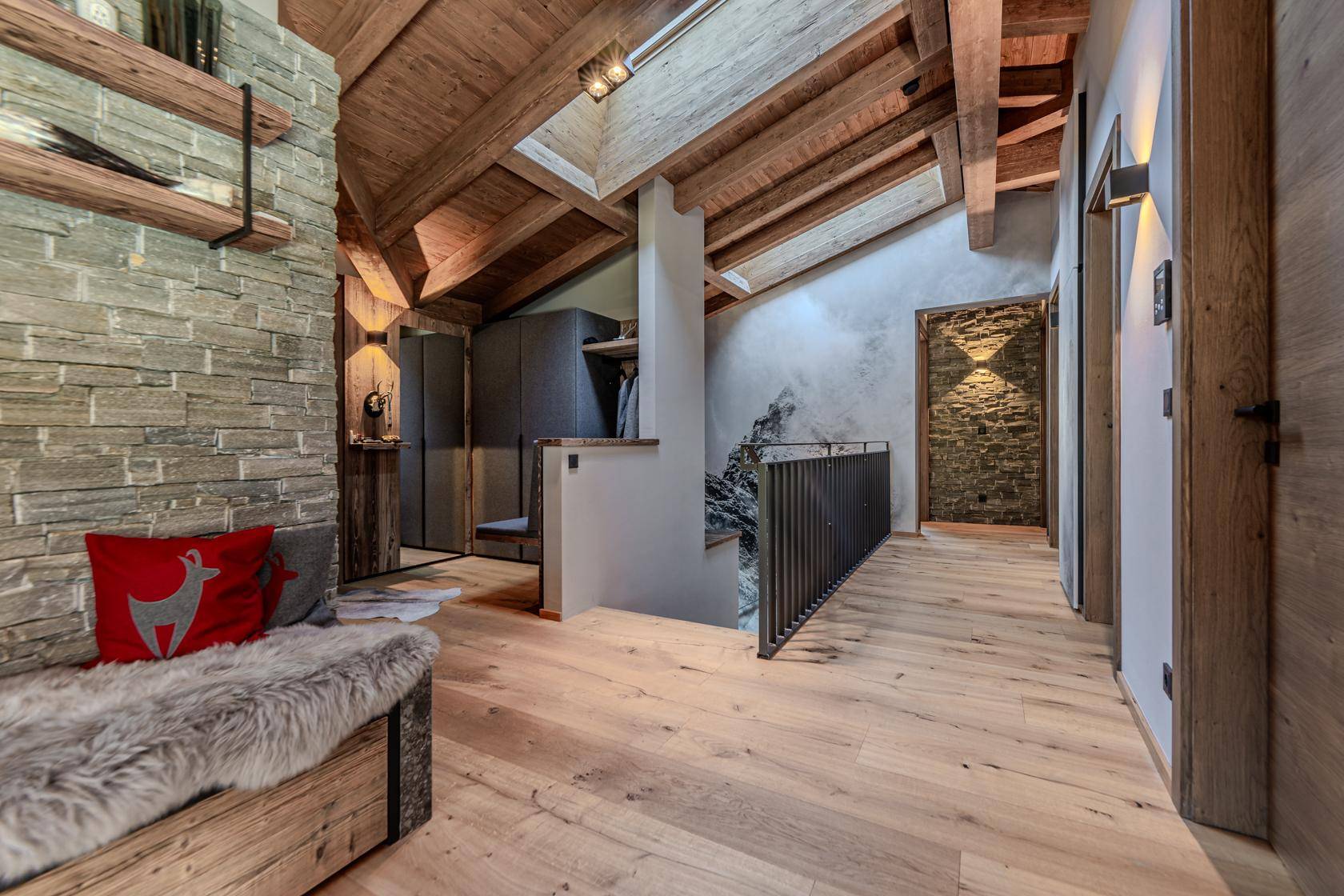 Geräumiger Flur mit Holzboden, Steinwand und offenem Treppenbereich, der das Chalet-Ambiente unterstreicht.