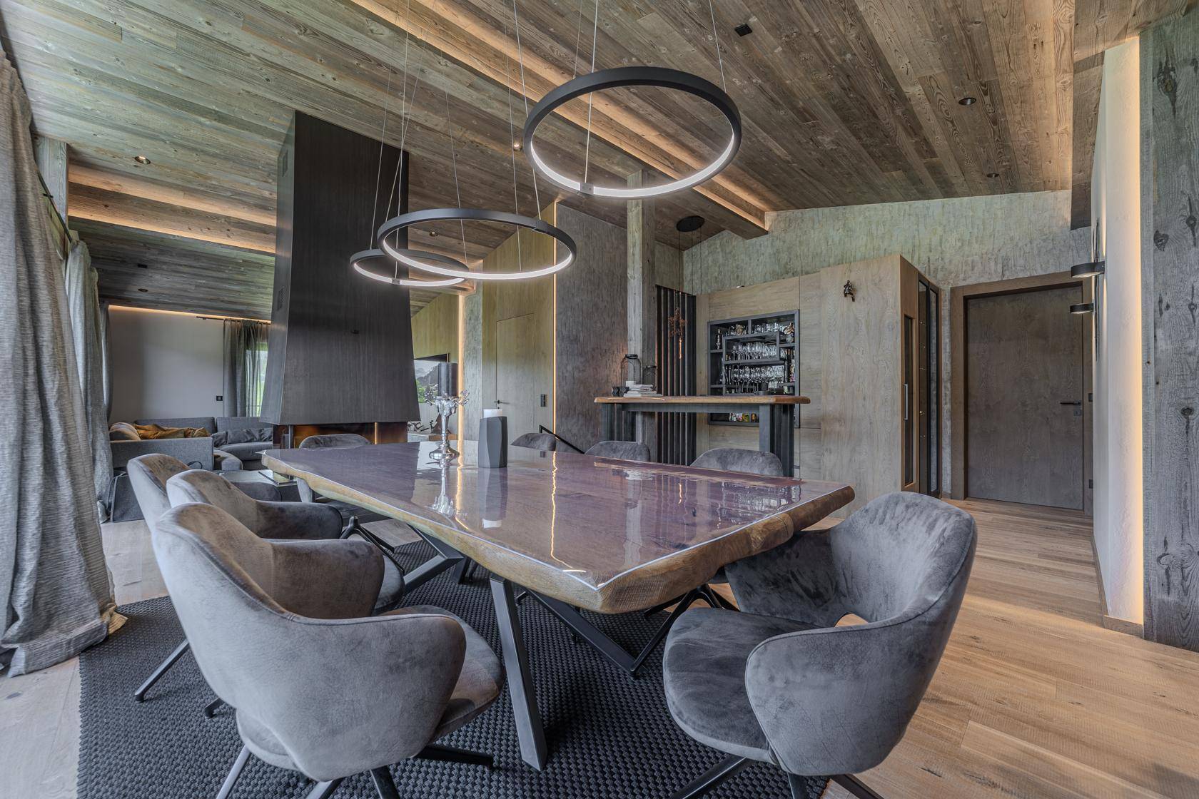 Geräumiger Essbereich mit großem Holztisch, Kamin und einer eleganten Bar im offenen Wohnkonzept.