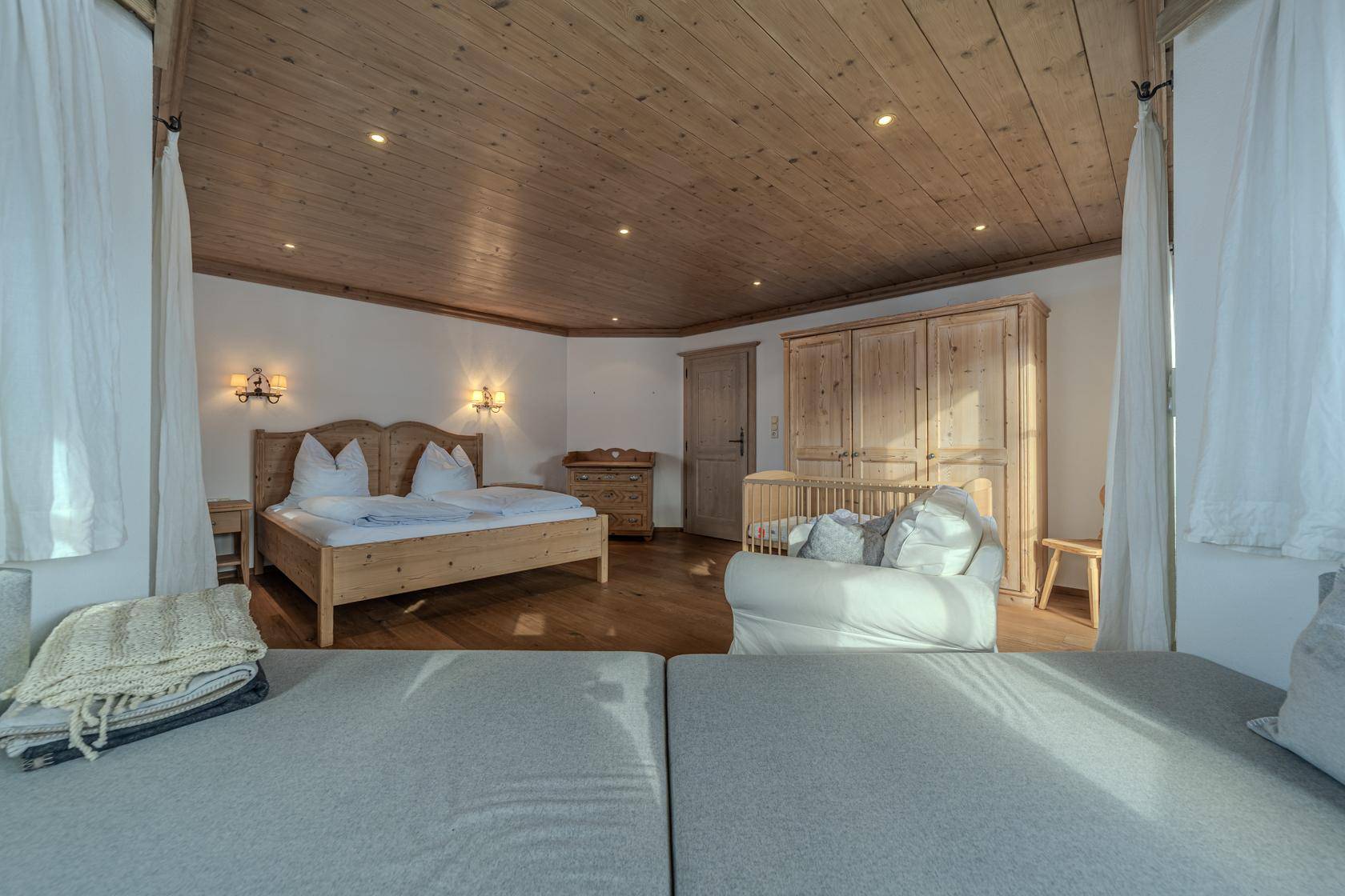 Gemütliches Schlafzimmer im Landhausstil mit Holzbett, Holzdecke und zusätzlichem Schlafsofa.