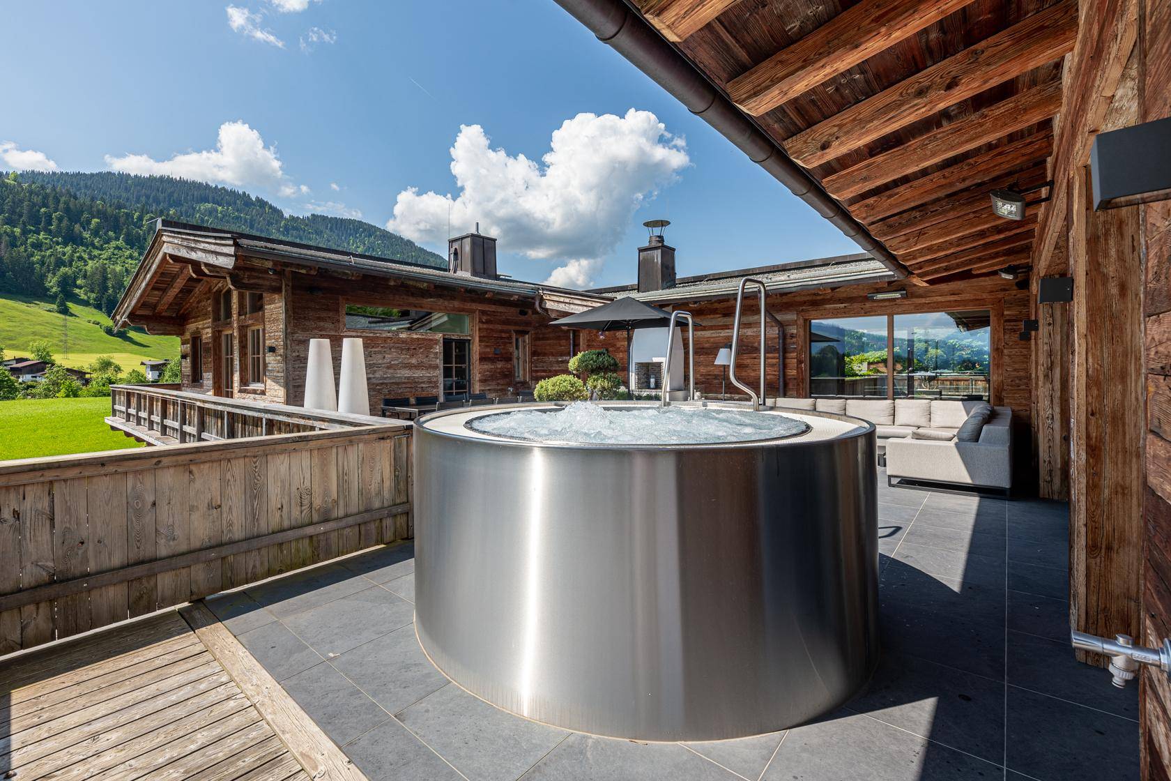 Exklusive Terrasse mit Whirlpool und Panoramablick auf die umliegende Berglandschaft.