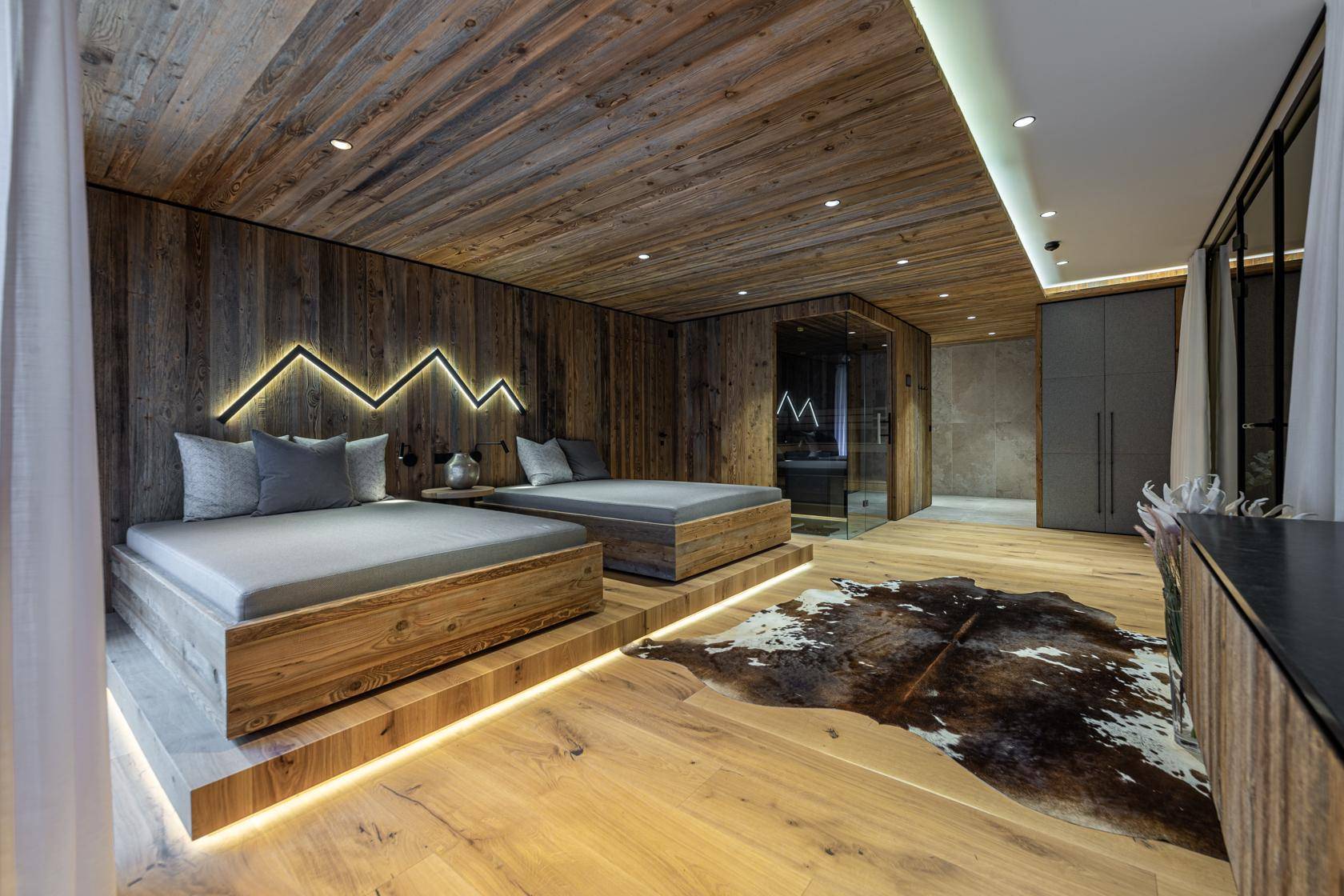 Moderner Wellnessbereich mit zwei Liegebetten, Sauna und indirekter Beleuchtung.