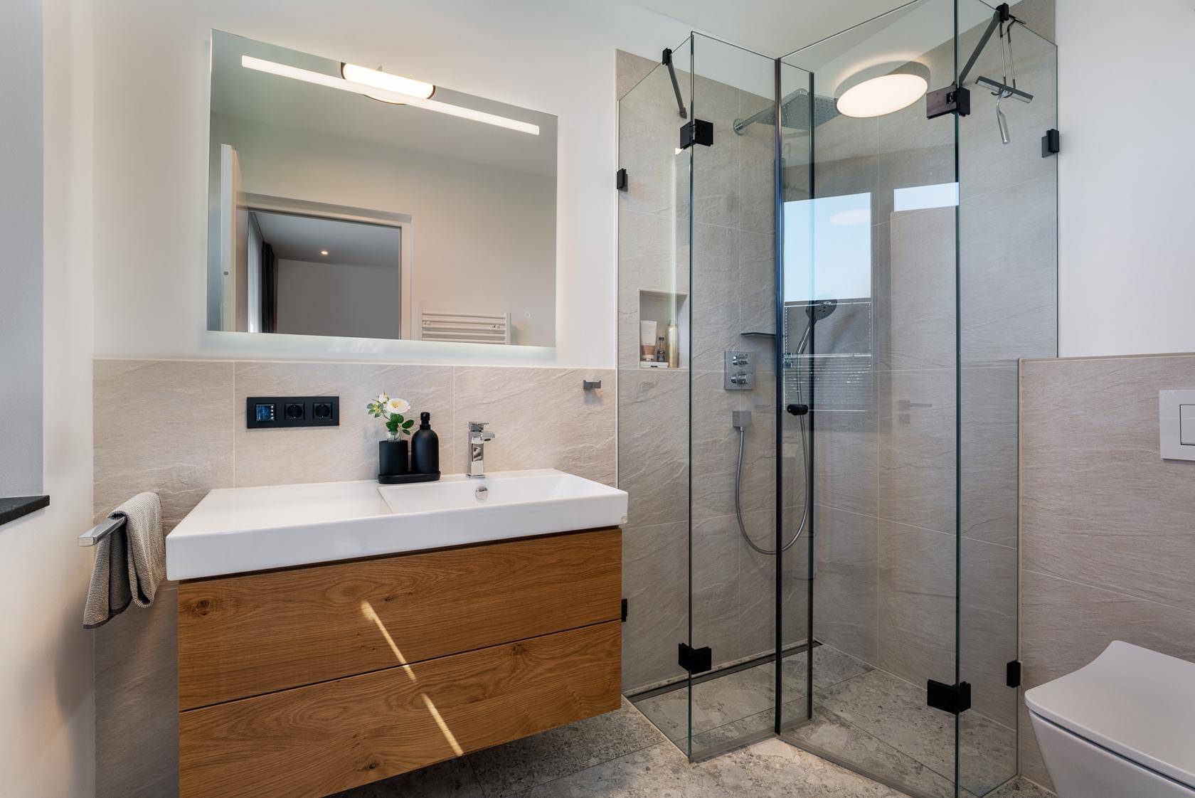 Modernes Badezimmer mit begehbarer Dusche, Holzwaschtisch und eleganten Fliesen.