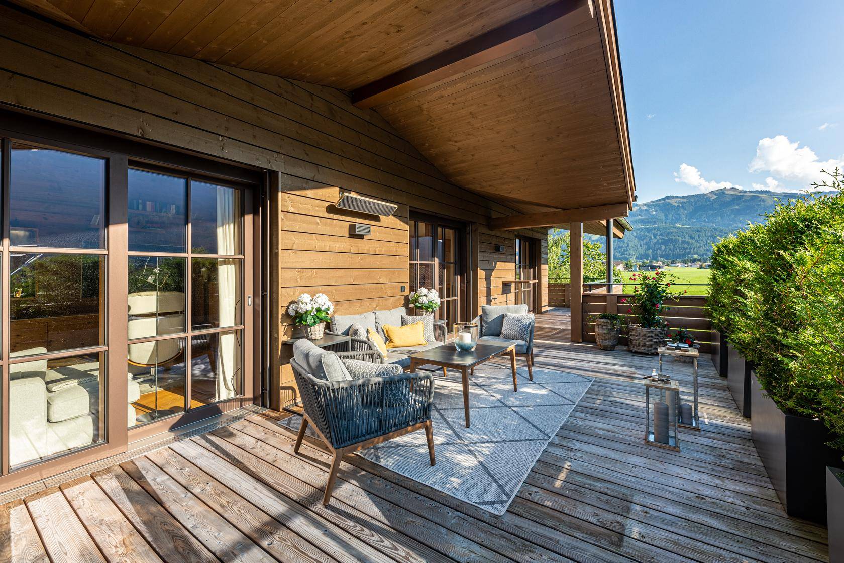 Große Holzterrasse mit bequemen Sitzmöbeln und weitem Blick auf die umliegende Berglandschaft.