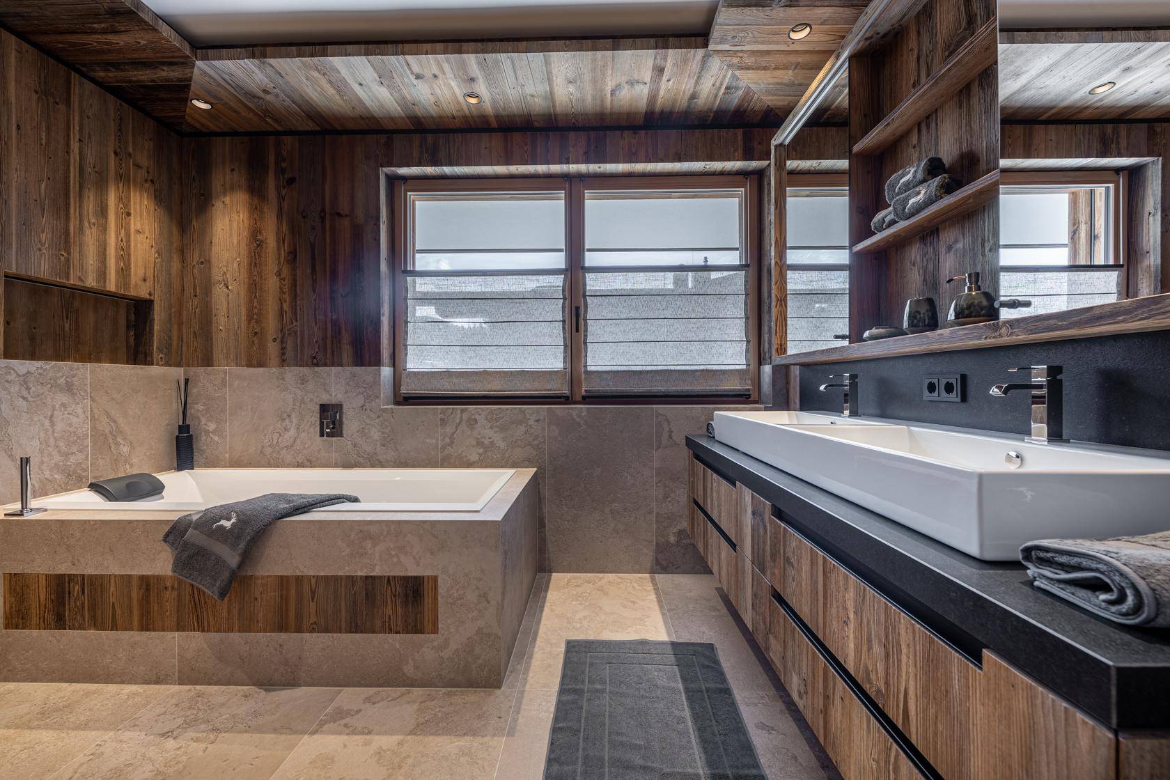 Modernes Badezimmer mit Doppelwaschbecken, Badewanne und Holzvertäfelung.