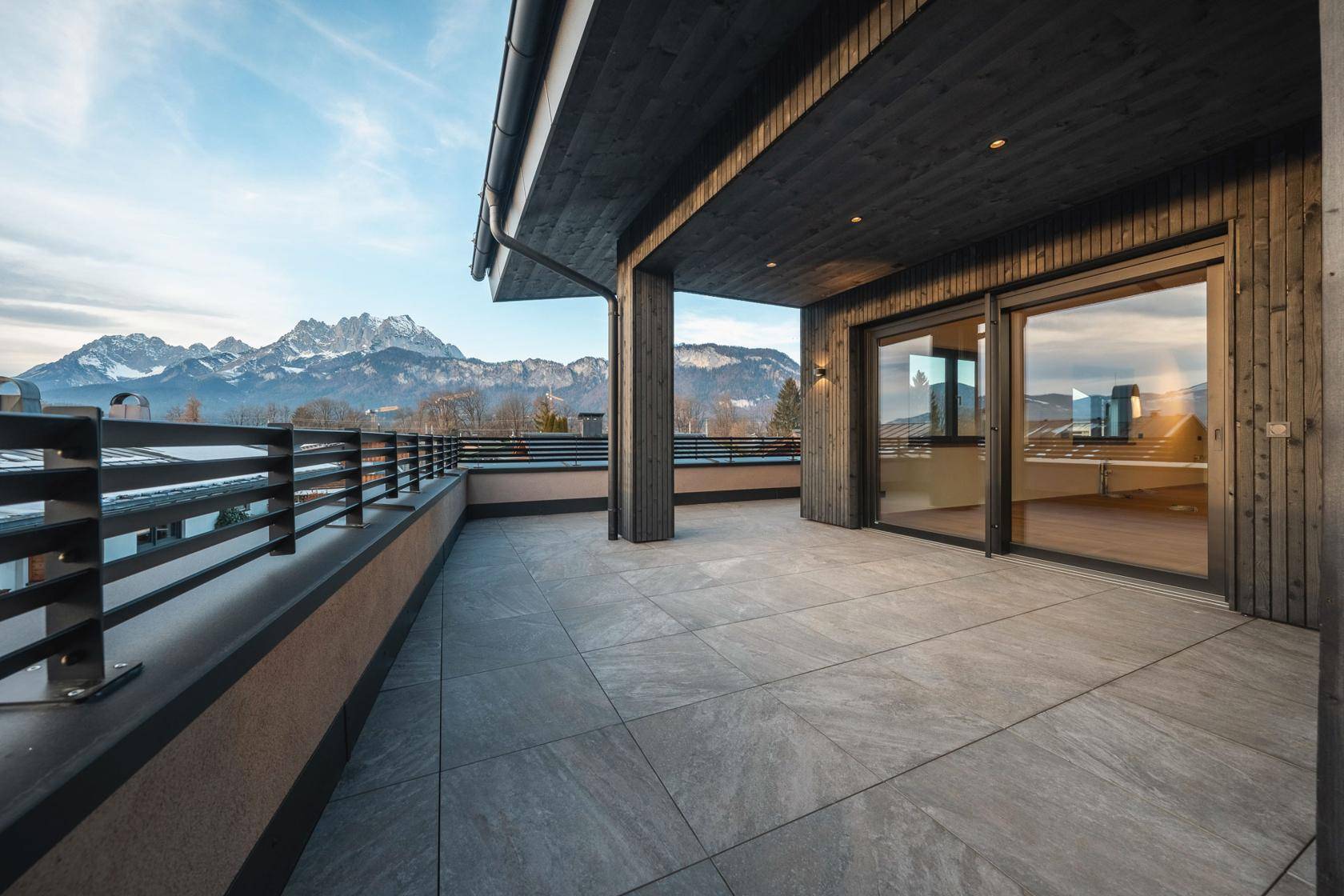 Geräumige Dachterrasse mit Fliesenboden und atemberaubendem Panoramablick auf die umliegenden Berge.