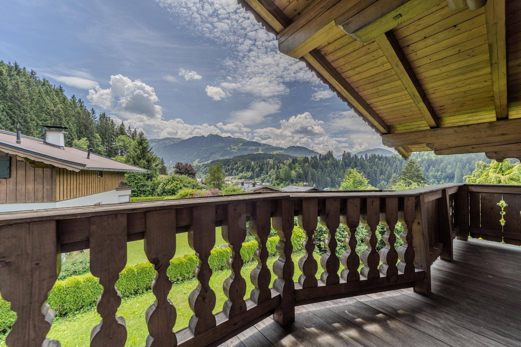 Traditioneller Holzbalkon mit malerischem Ausblick auf die bewaldeten Berge und das Tal.