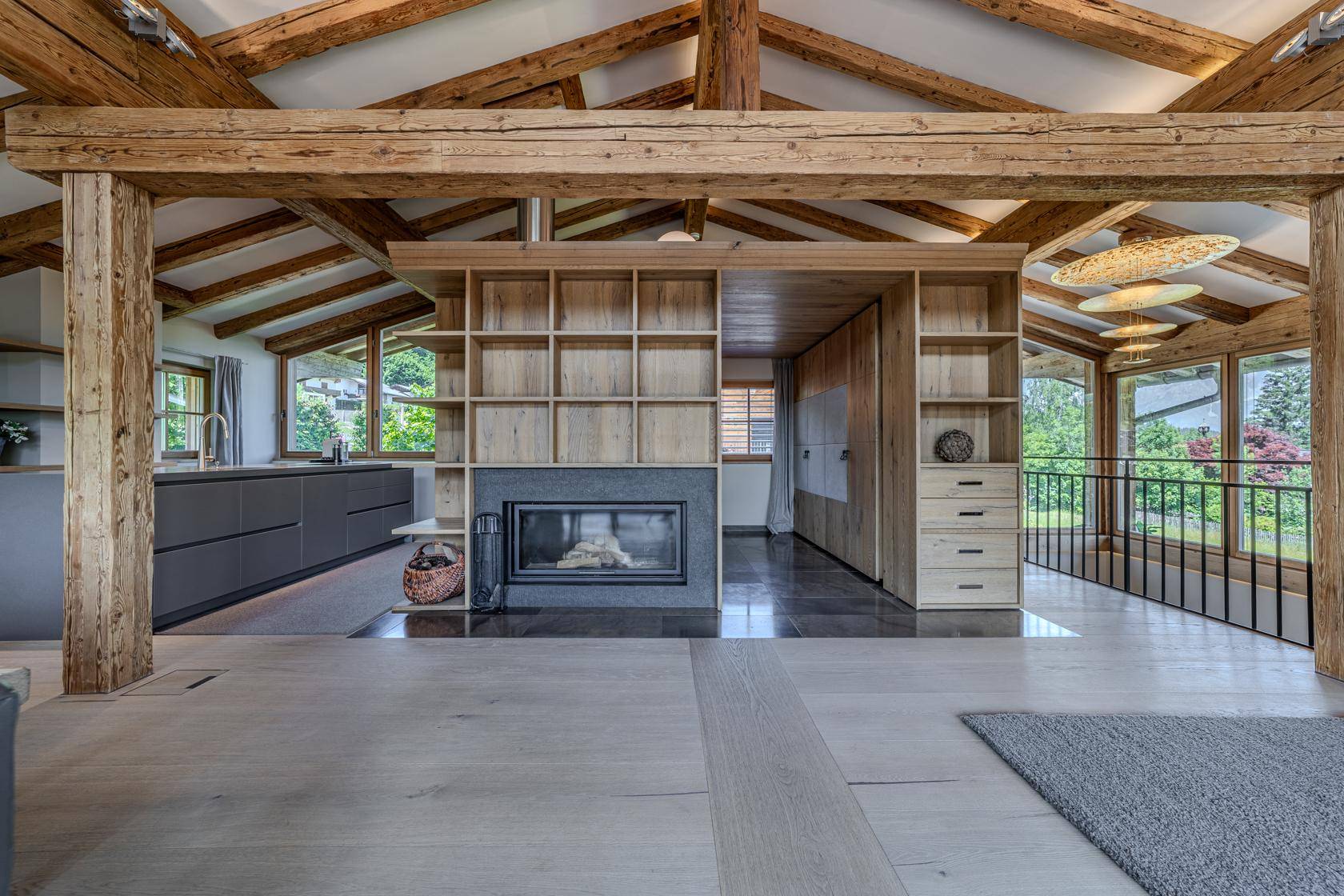 Offener Wohnbereich mit integriertem Kamin, Holzbalken und moderner Küche.