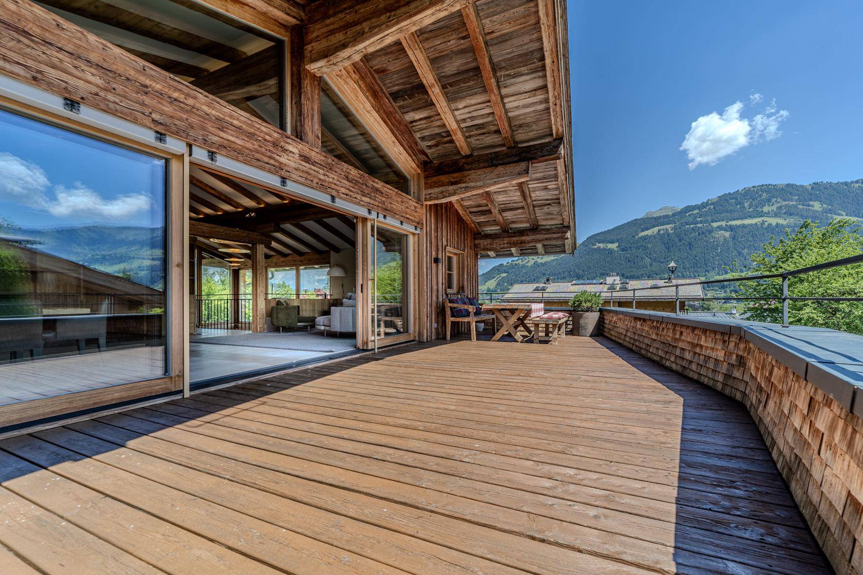Große Holzterrasse mit Sitzgelegenheiten und weitem Blick auf die Berge.