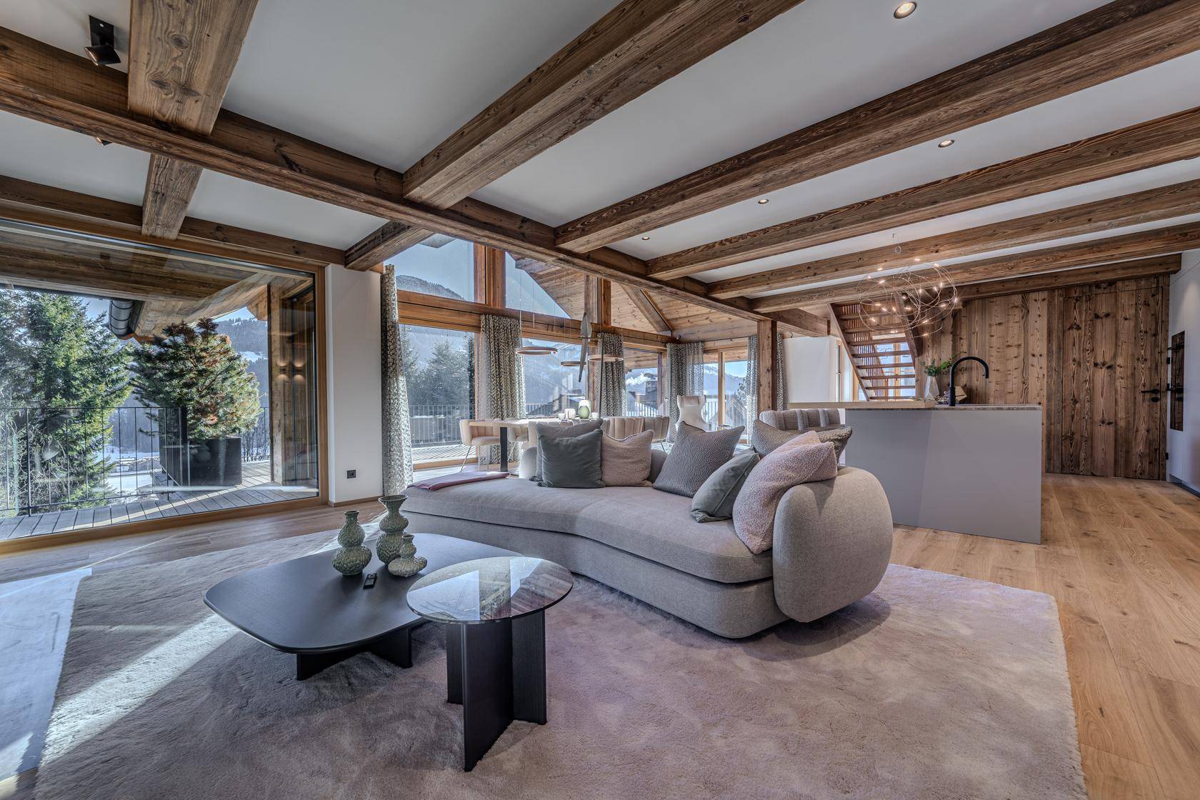 Heller, offener Wohnbereich mit modernem Sofa, Holzbalken und Zugang zur Terrasse.