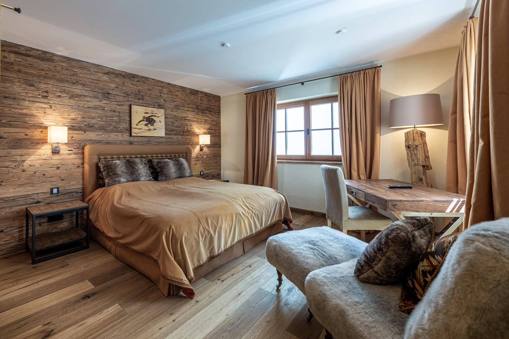 Gemütliches Schlafzimmer mit Holzwand, großem Bett und rustikalem Schreibtisch, ideal zum Entspannen.