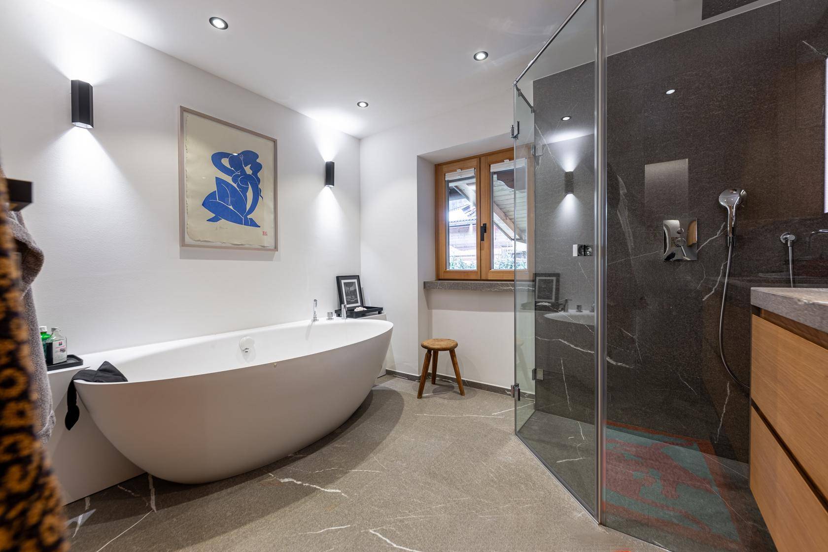 Modernes Badezimmer mit freistehender Badewanne, begehbarer Dusche und Fenster, elegant gefliest.
