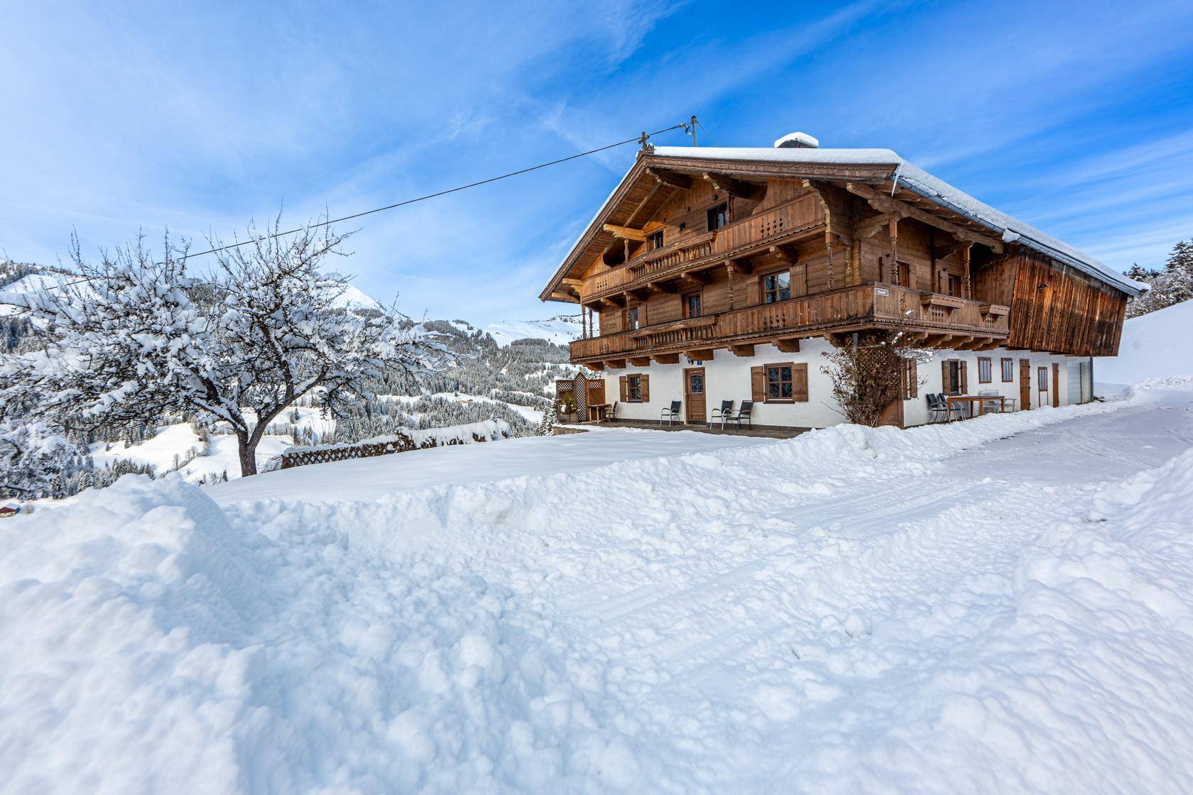 Traditionelles Holzhaus im alpinen Stil, umgeben von tiefem Schnee und einer winterlichen Berglandschaft.