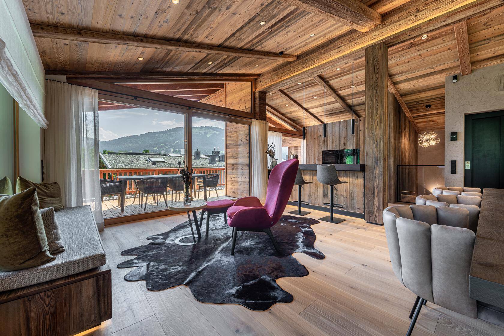 Gemütlicher Wohnbereich mit Bar, Holzboden und Zugang zu einem sonnigen Balkon.