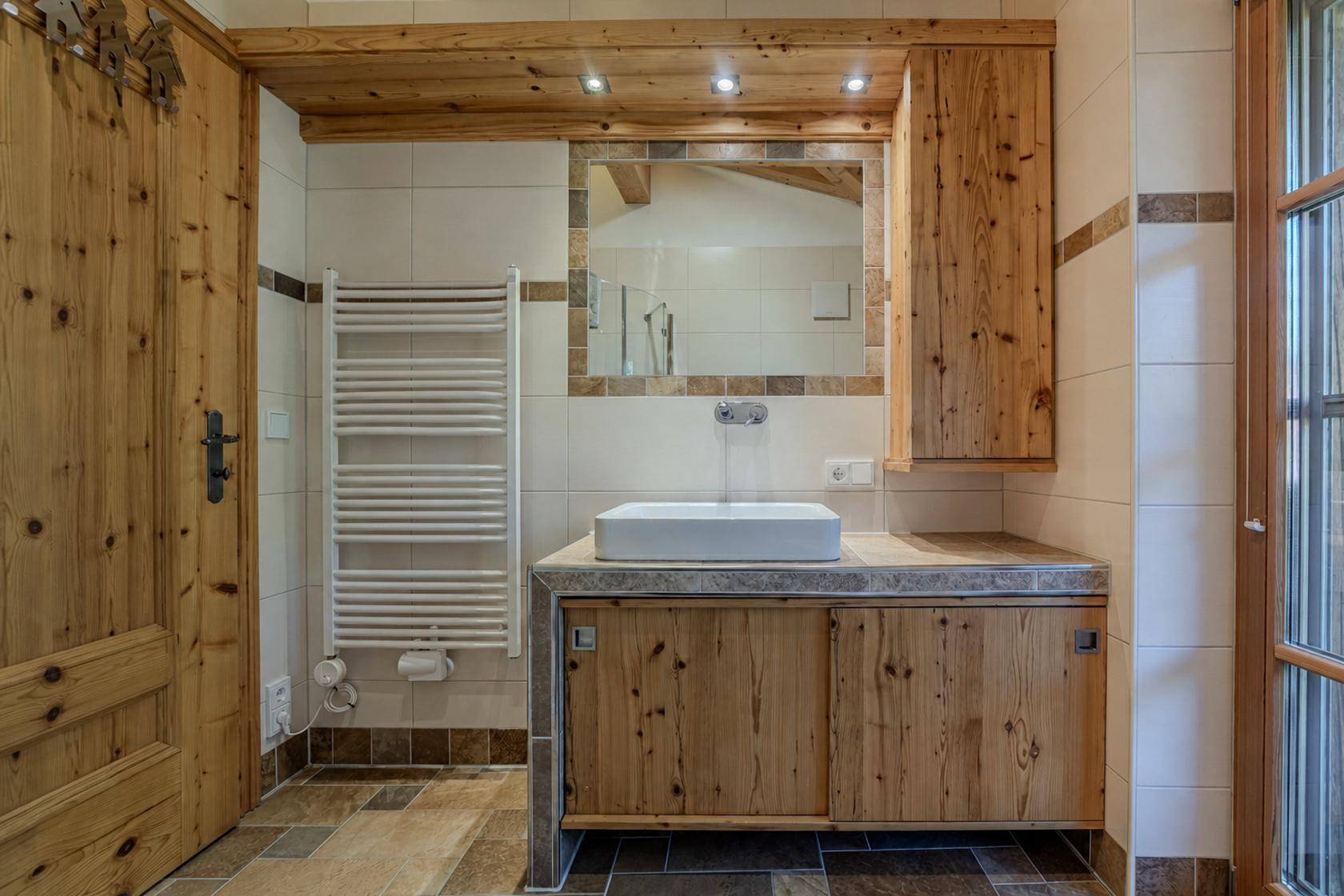 Badezimmer im Landhausstil mit Holzwaschtisch, Fliesenboden und Handtuchheizkörper.