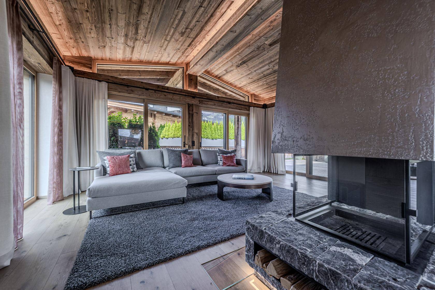 Gemütliches Wohnzimmer mit großem Sofa, modernem Kamin und Holzbalkendecke.