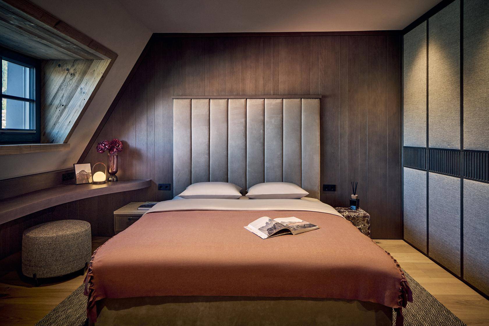 Stilvolles Schlafzimmer mit Holzwänden, Dachschräge und integrierten Schränken, sehr gemütlich.