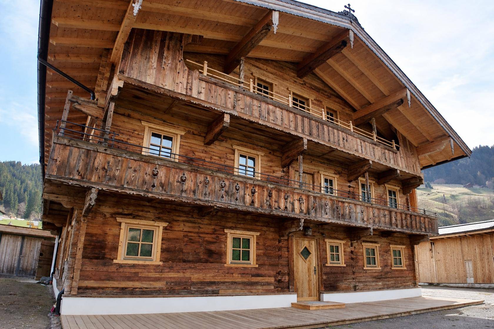 Traditionelles Holzchalet mit mehreren Balkonen und aufwendigen Holzschnitzereien in alpiner Umgebung.