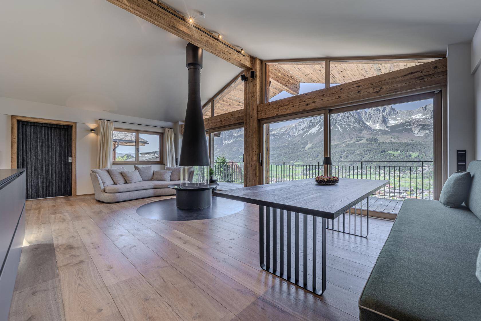 Heller Wohn-Essbereich mit Holzboden, gemütlicher Sitzecke und Panoramablick auf die Berge.