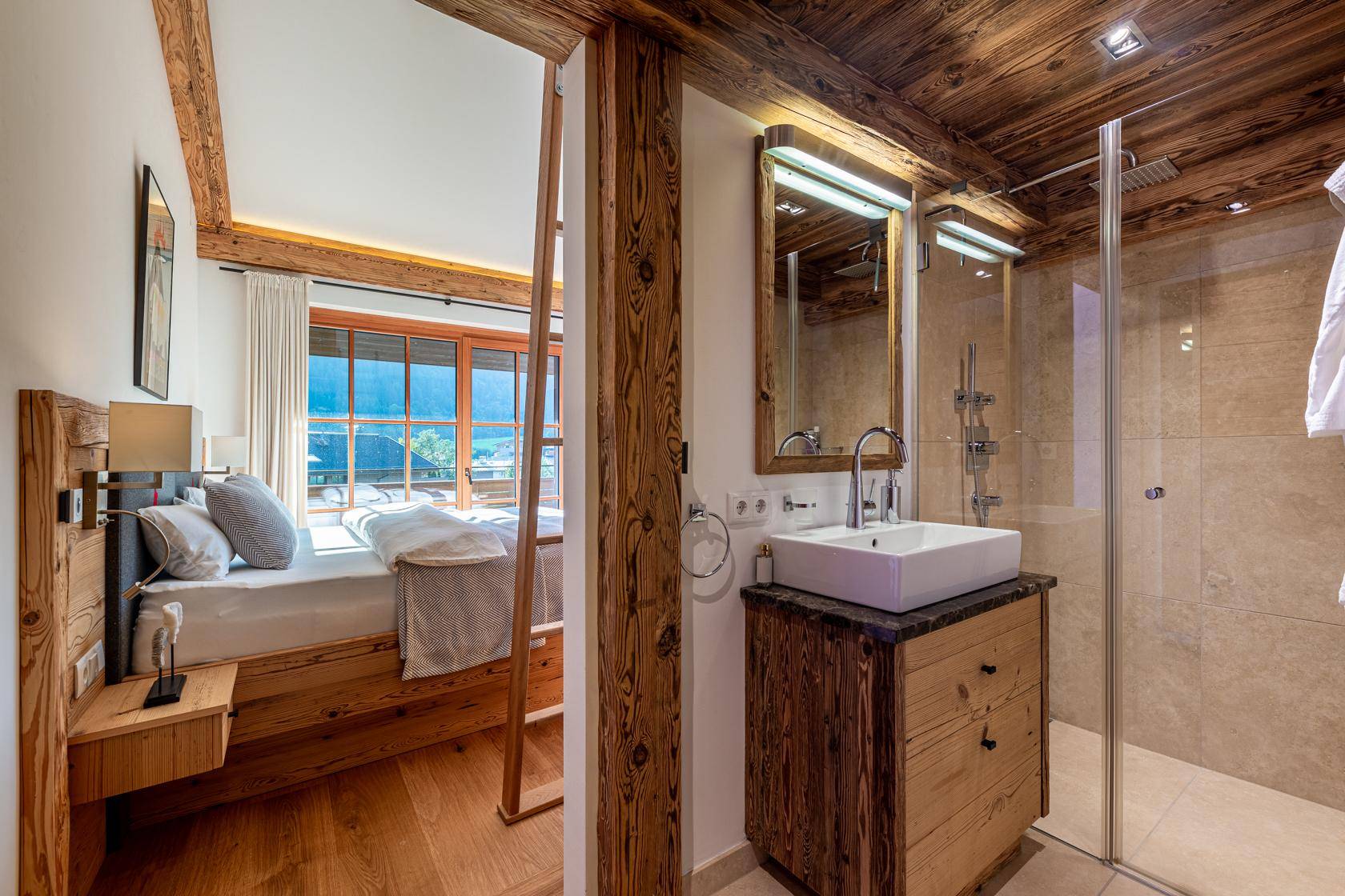 Schlafzimmer mit Holzboden und angrenzendem Badezimmer mit moderner Dusche.